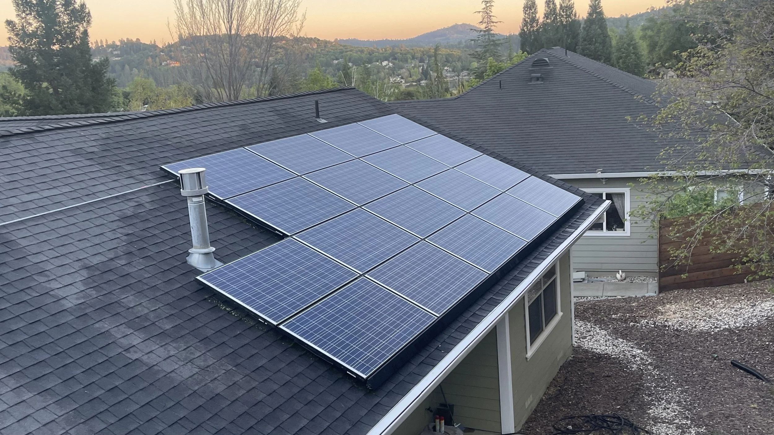 Rooftop with solar panels on a house in a suburban neighborhood during sunset
