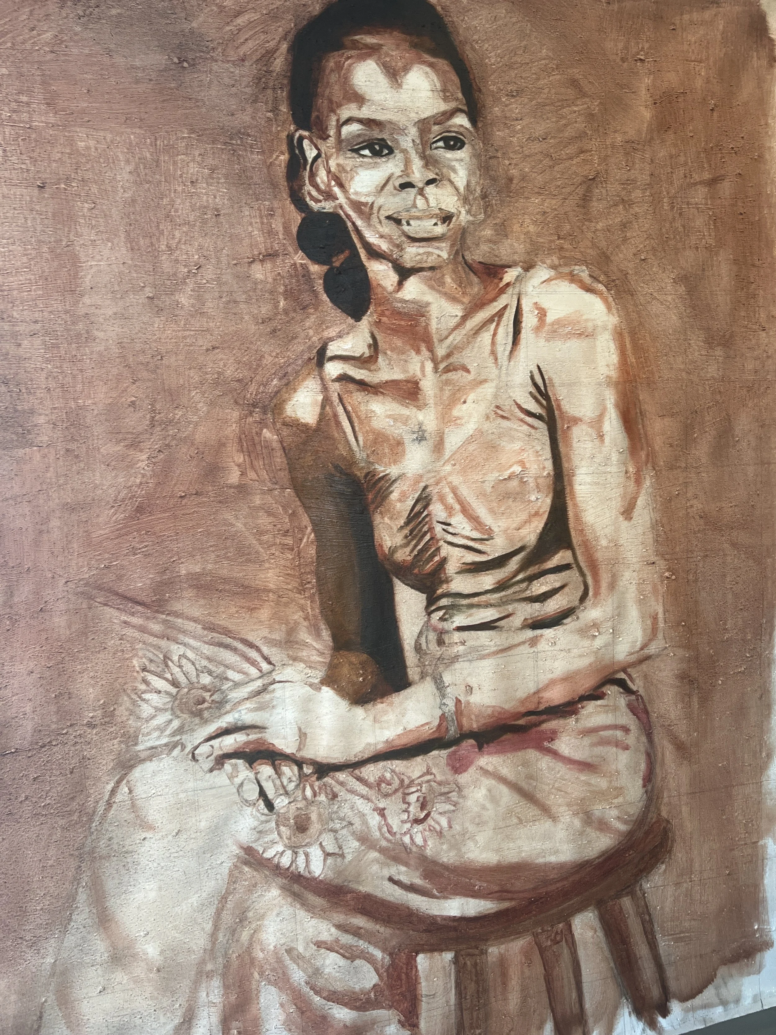 A painting of a woman with dark hair pulled back, smiling and looking slightly to the right, sitting with her arms crossed on a surface decorated with a sunflower and a butterfly.