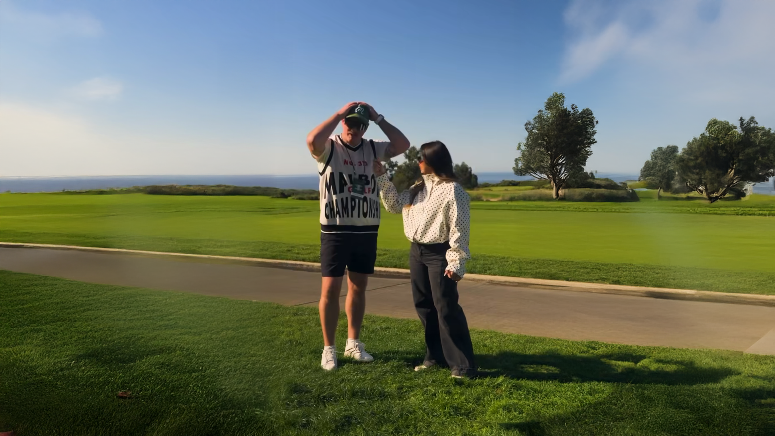 An Art director getting interviewed by a woman on a golf course.