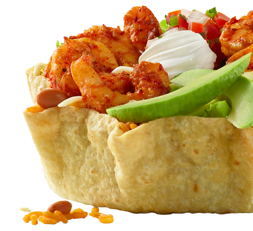 close-up of a tostada with seasoned shrimp, shredded cheese, diced tomatoes, chopped green onions, sour cream, and sliced avocado in a crispy taco shell