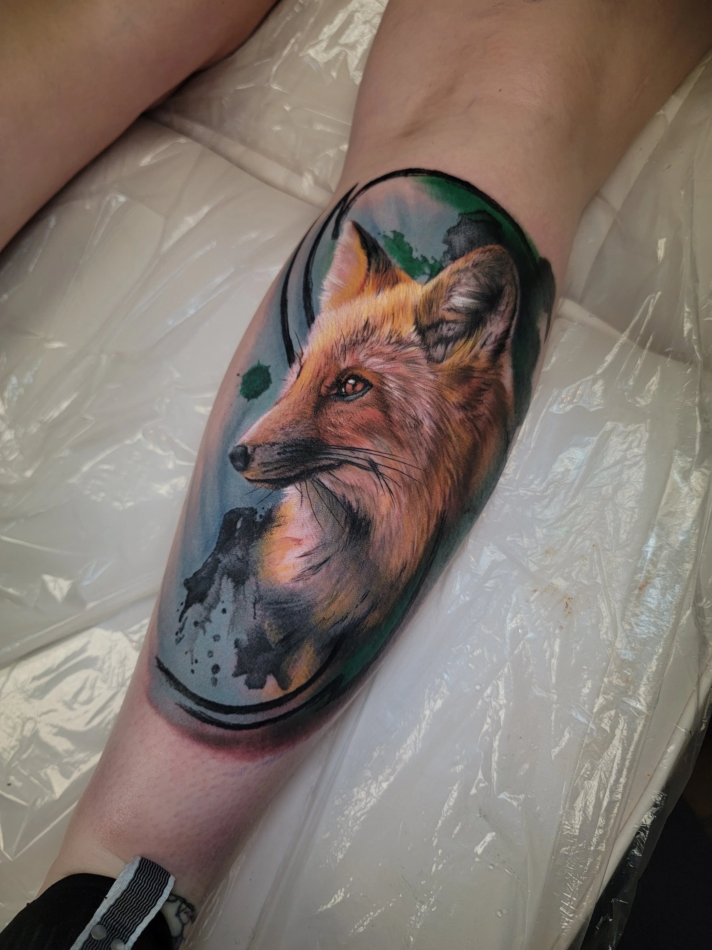 Tattoo of a fox's head on a person's leg, with colorful background