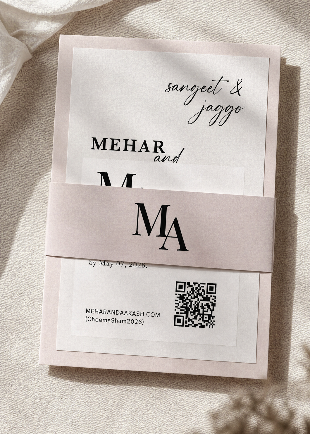Invitation card for a wedding of Sangeet and Jaggod, with the names Mehar and M. prominently displayed. The card is partially covered by a pink band with large initials 'M' and 'A'. A QR code and a website URL are visible at the bottom.
