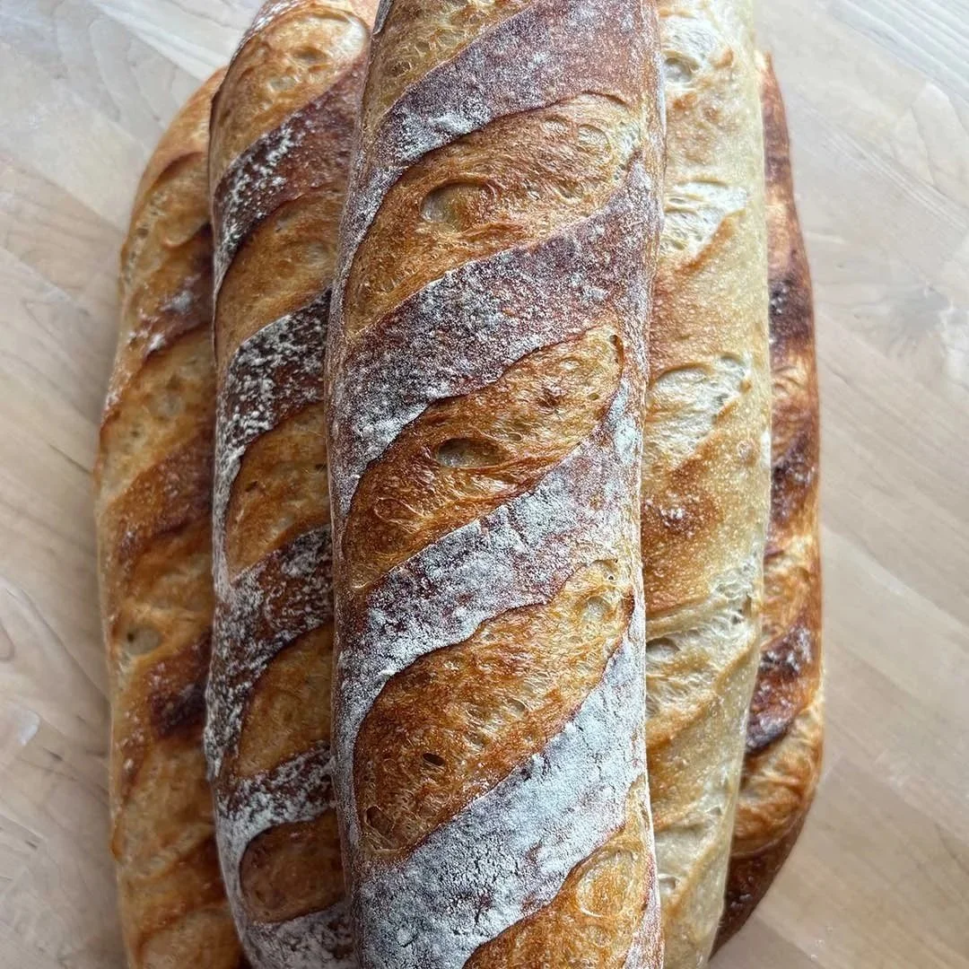 Loaves of flute maison bread, stacked on top of each other.