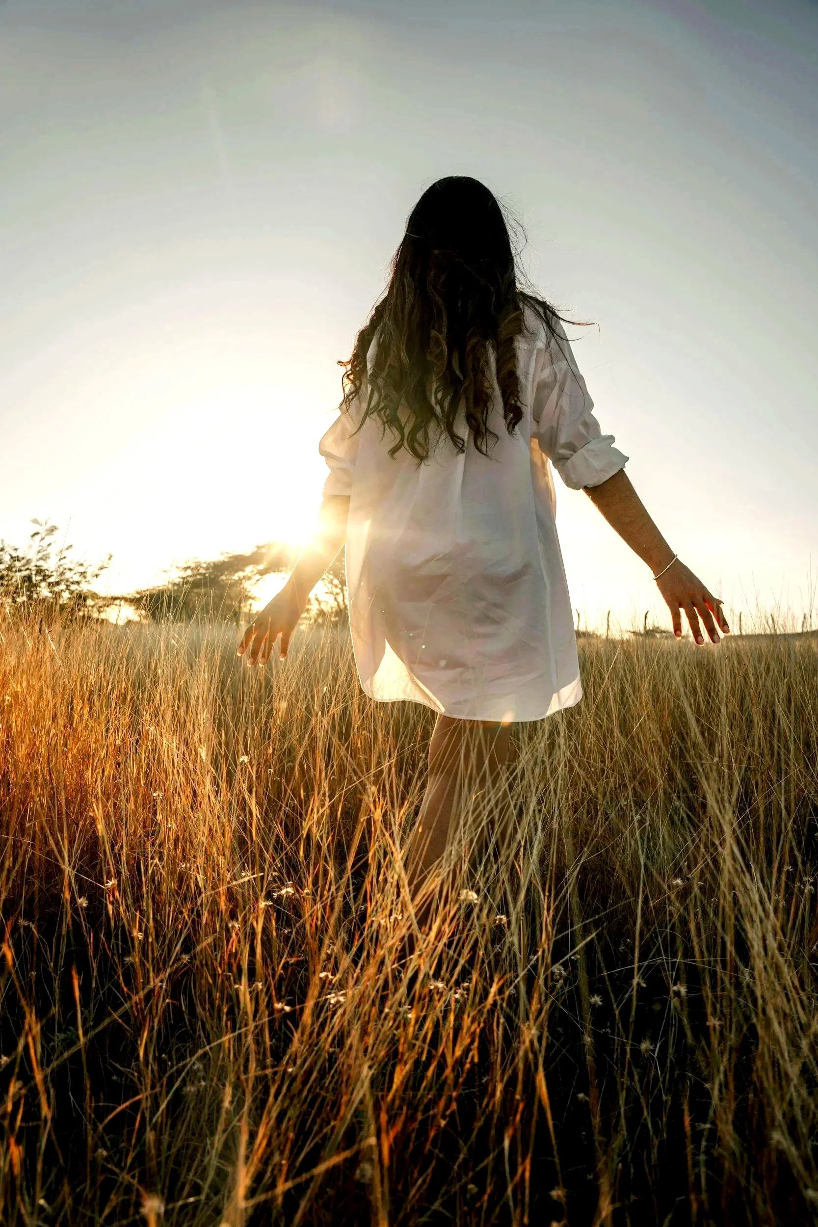 Woman in a field at sunset representing healing, wholeness and emotional freedom after Held retreat