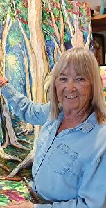 Woman with blonde hair smiling in front of a colorful painted forest scene