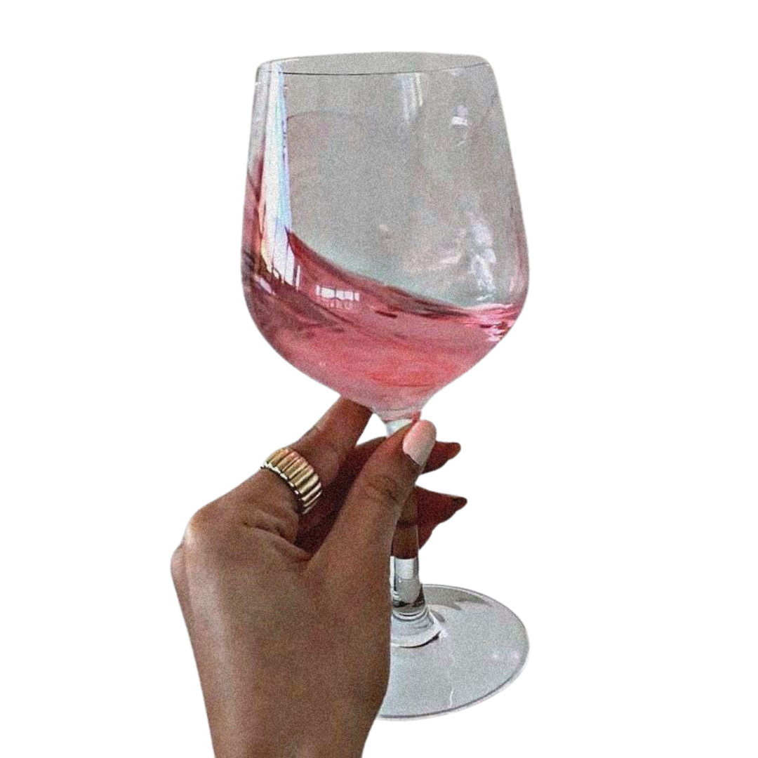 Close-up of a hand holding a glass of pink wine against a black background.