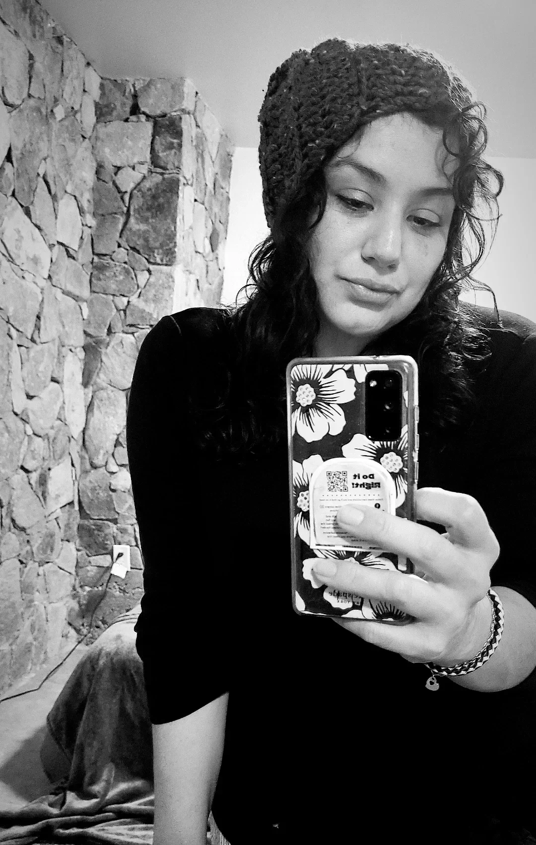 Zarina Zertuche with curly hair wearing a beanie taking a casual mirror selfie in black and white.