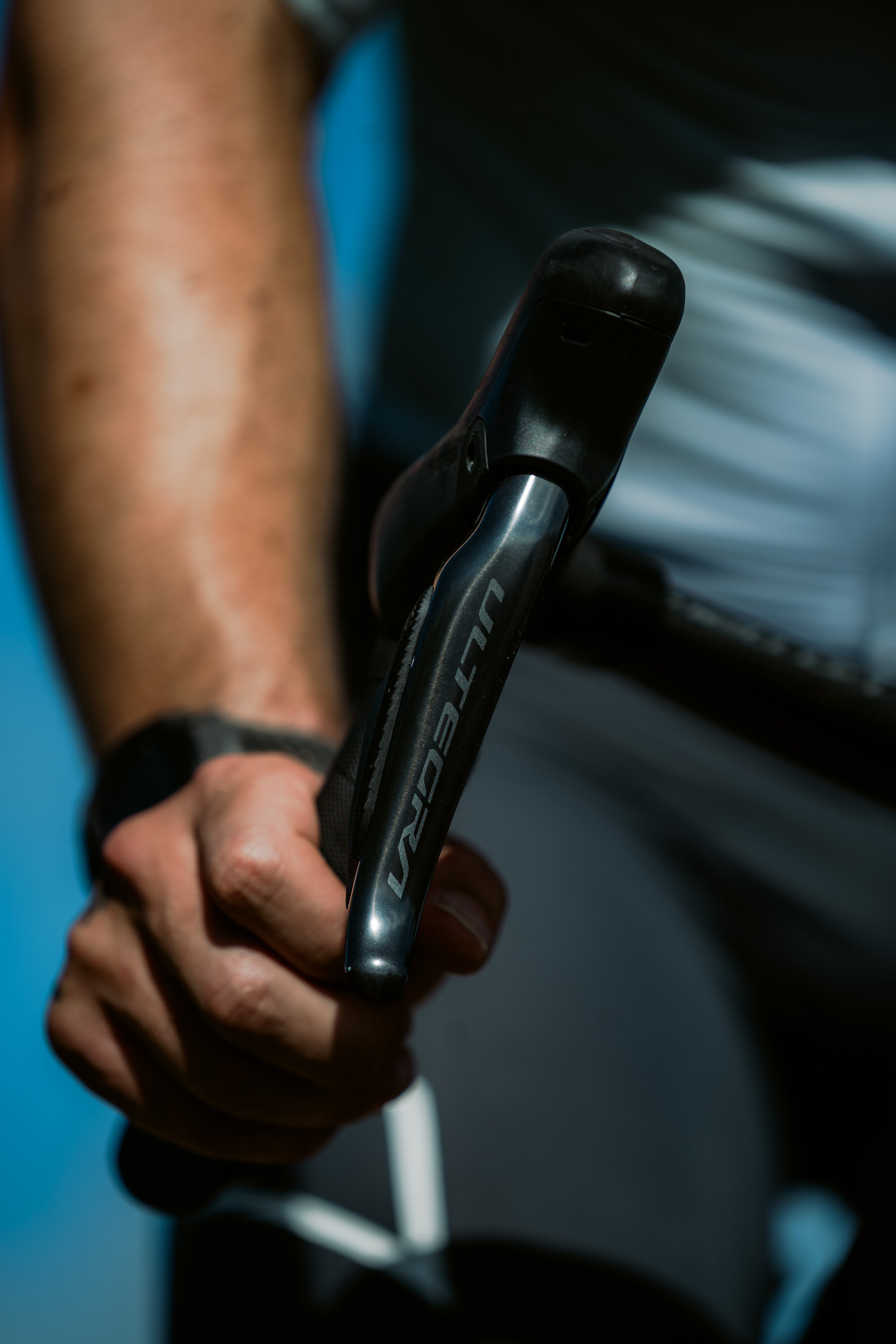 Close-up of a person holding a black and silver golf club, with a blurred background.