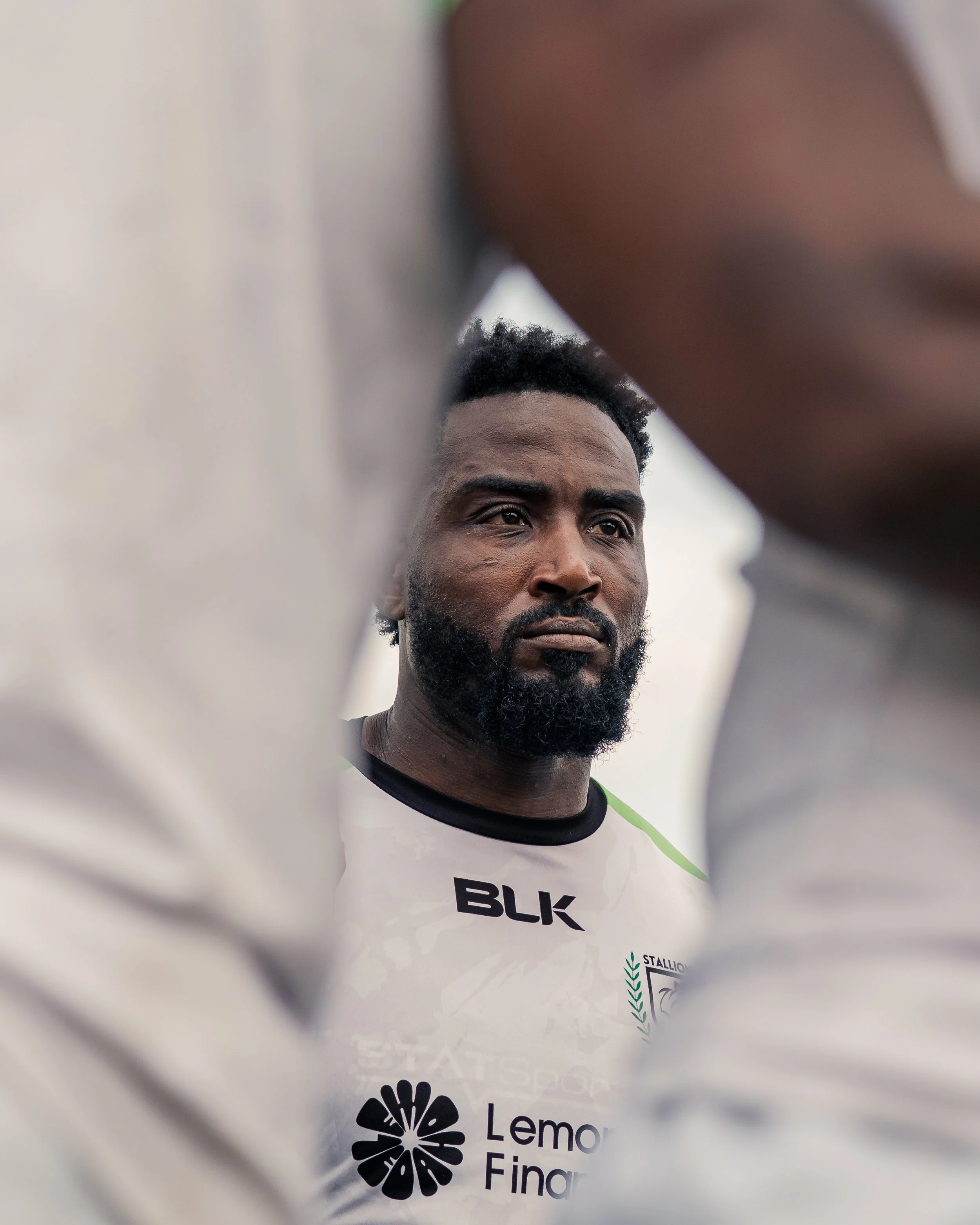 Close-up of a man's face partially obscured by a white shirt with logos, including 'BLK' and 'LemonFing'.