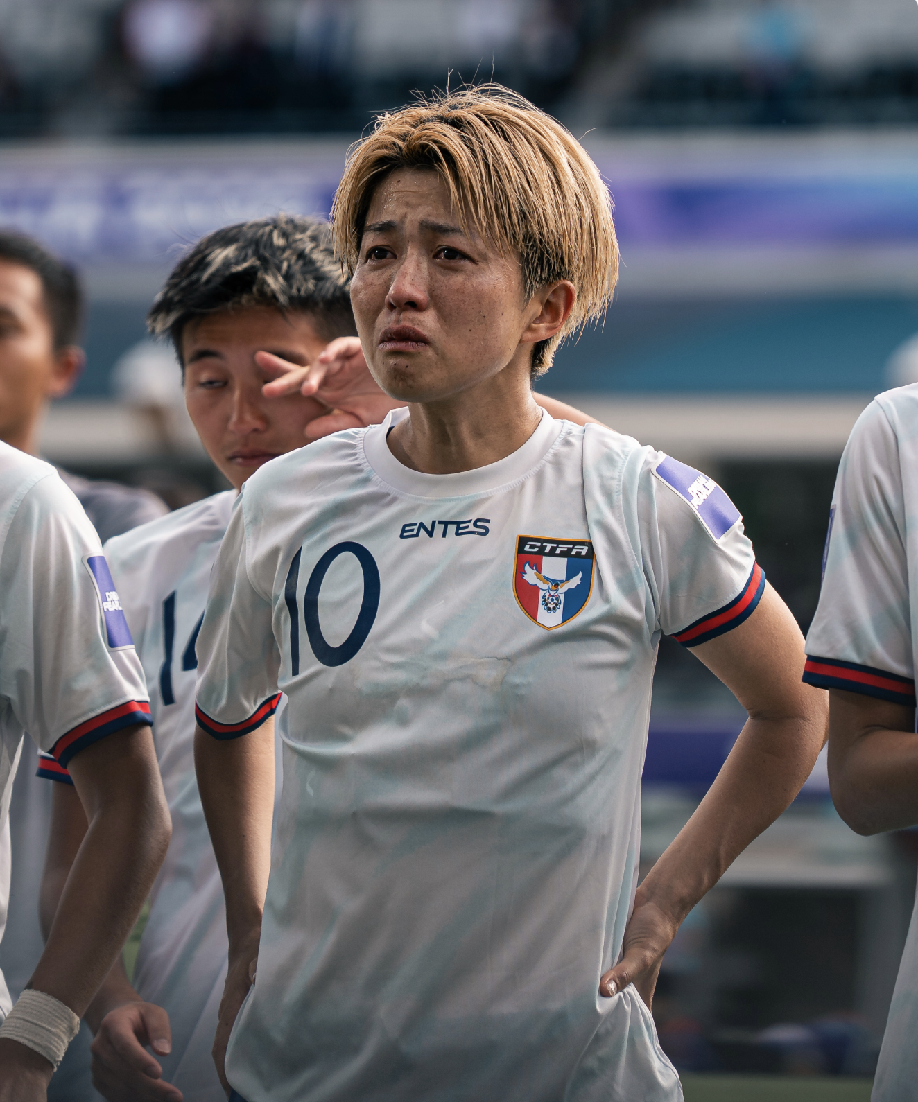 A female soccer player standing on the field with her team, wearing a white jersey with the number 10 and the South Korea flag patch, during a game or team lineup.