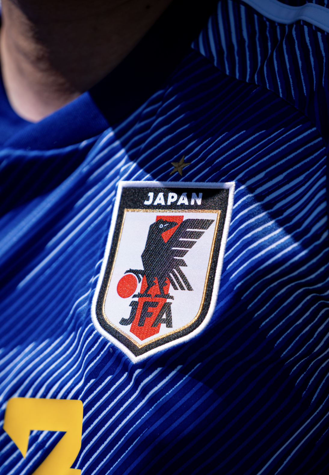 Close-up of a Japan soccer jersey featuring an embroidered patch with a black eagle and the Japanese flag, with the word 'JAPAN' on top.