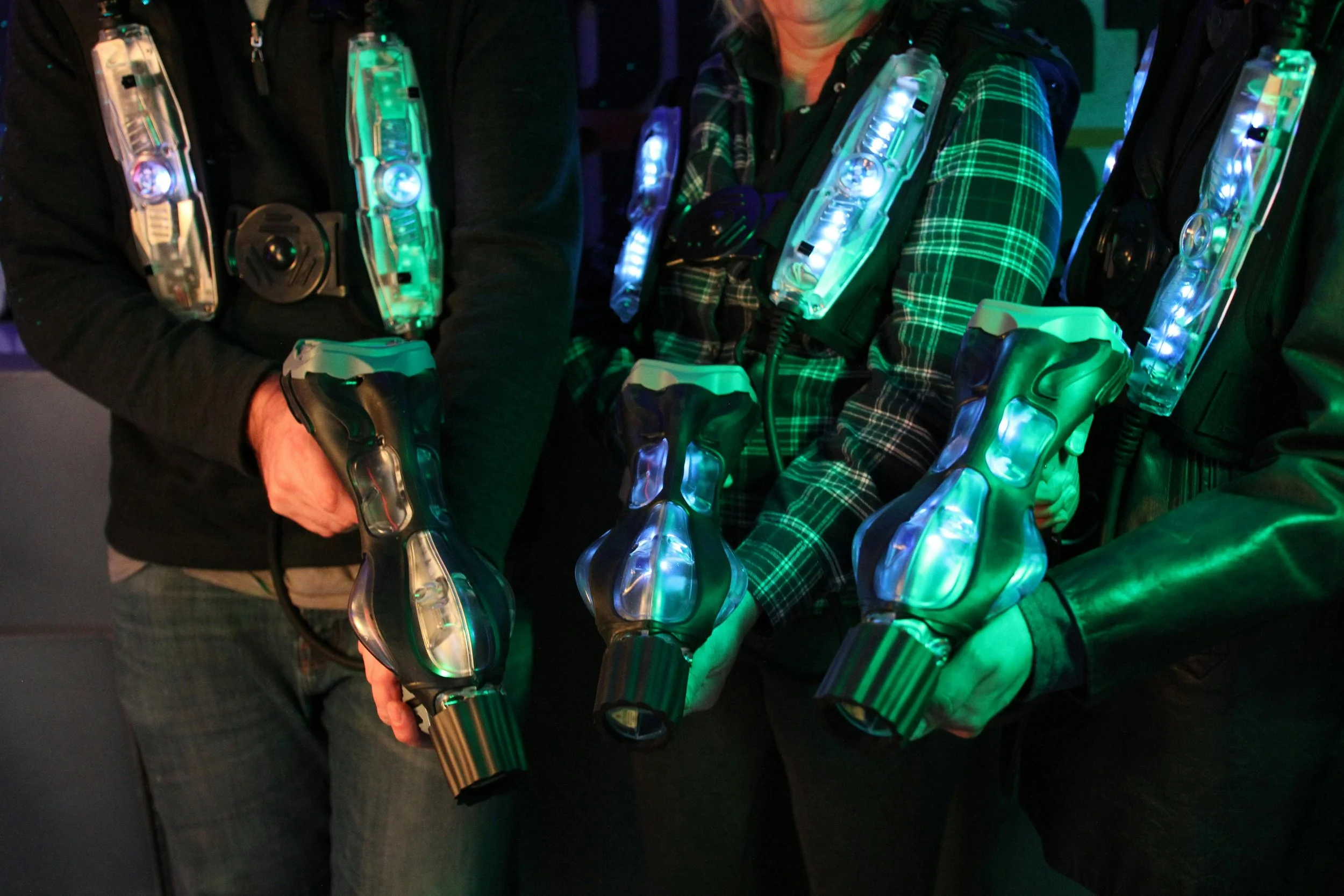 People are wearing futuristic LED-lit vests and holding laser guns, suggesting a laser tag or sci-fi themed activity in central alberta