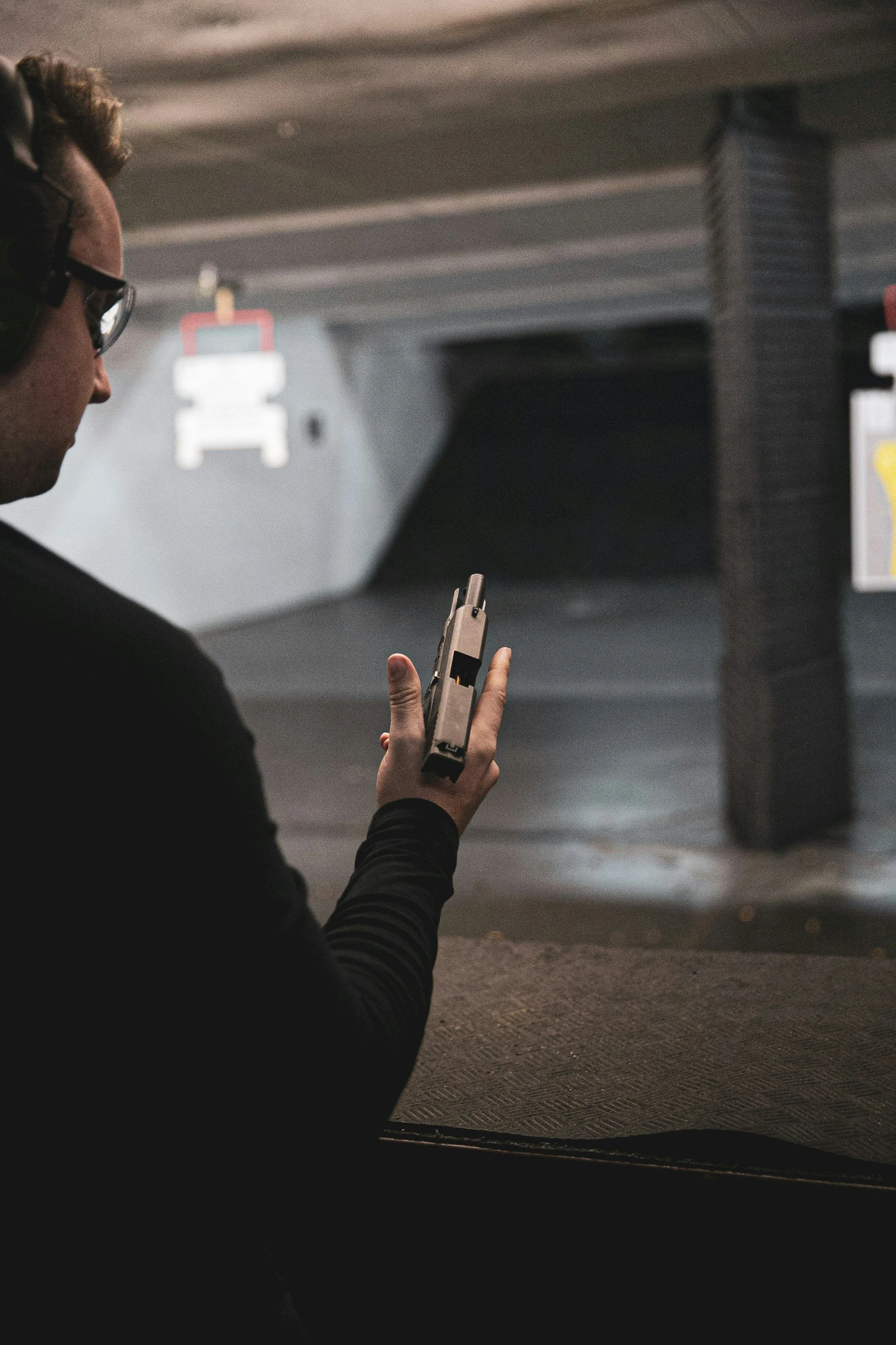 A person with glasses and a black jacket is reloading a hand gun while at a gun range in central alberta.