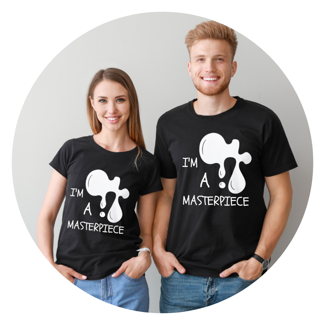 A young woman and man wearing matching black T-shirts with a paint splatter design and the words "I'm a masterpiece". They are smiling and standing against a light gray background.