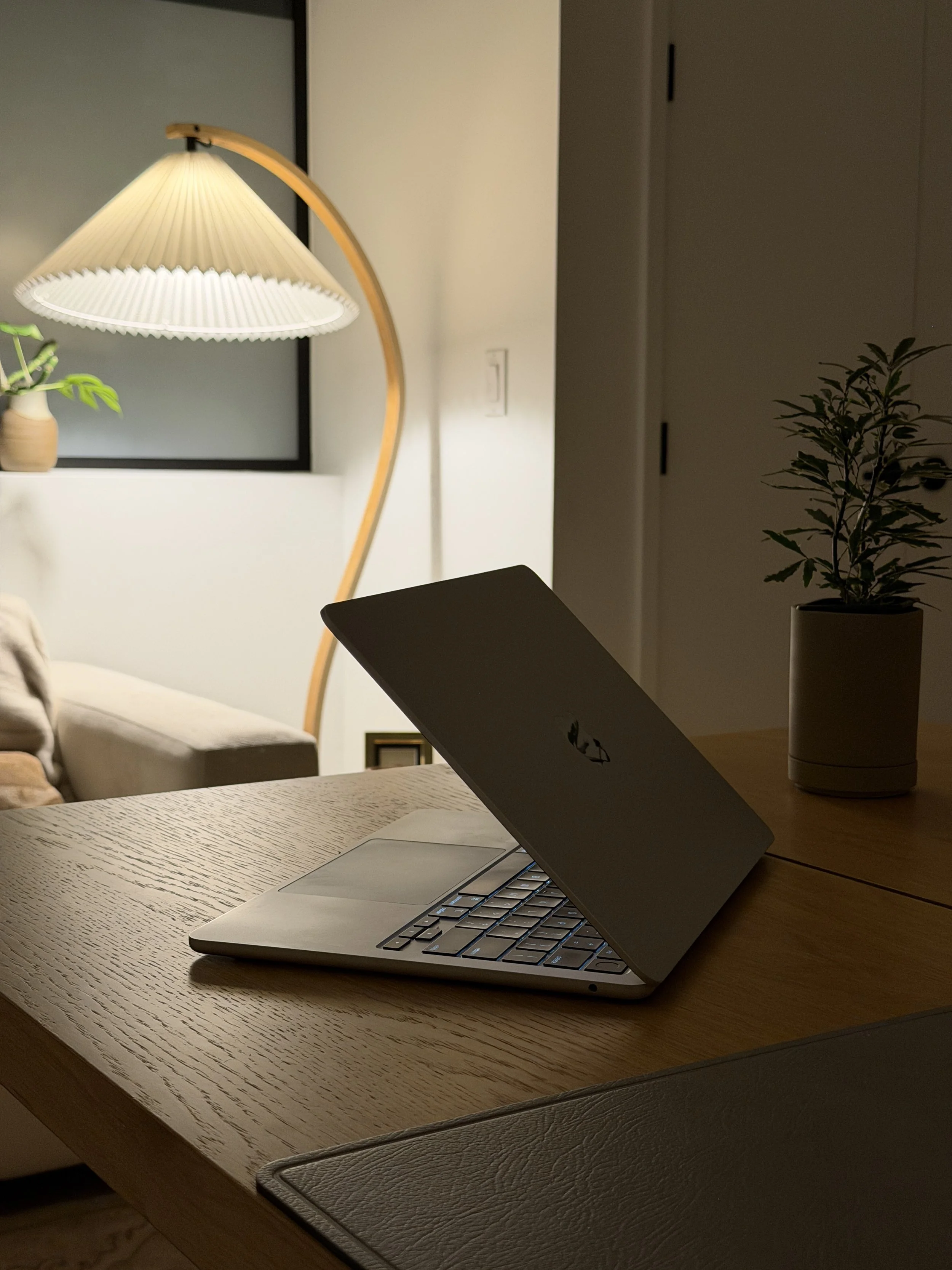 A laptop on a wooden table, an office lamp, a white couch in an office setting, showing the calm aesthetic of Julia Roger's practice and the peace of mind that comes with being a patient.