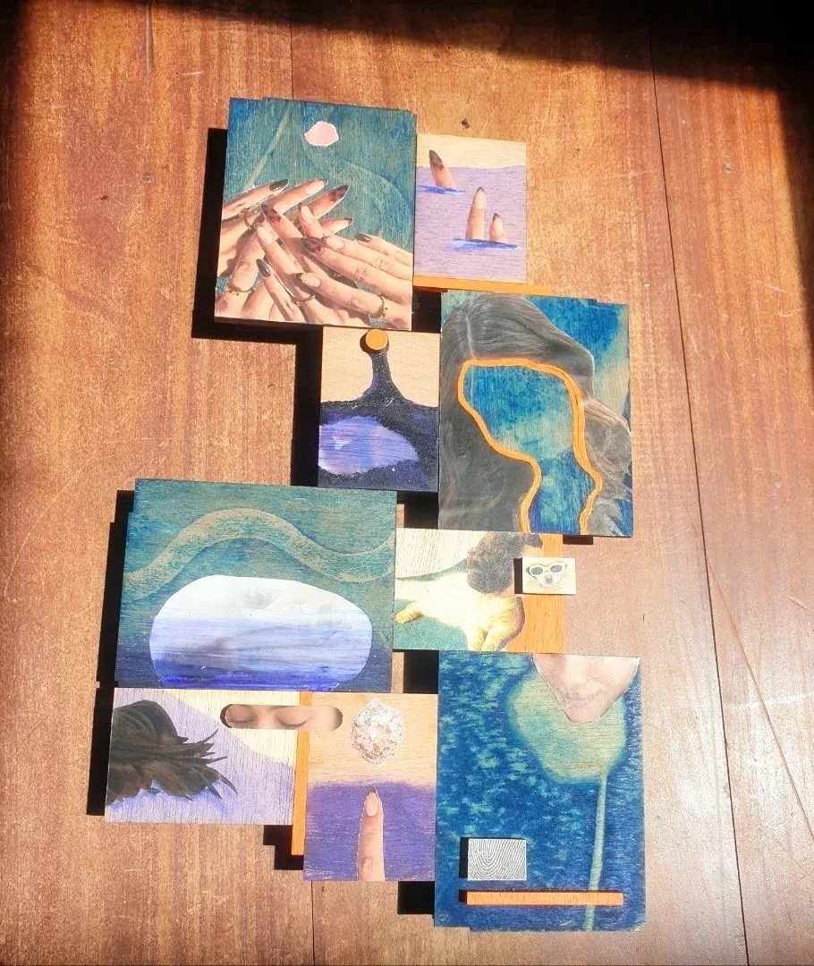 A collage of small art pieces arranged on a wooden surface, featuring paintings and photographs with abstract and human elements, including hands, a woman with a ponytail, and various landscapes.