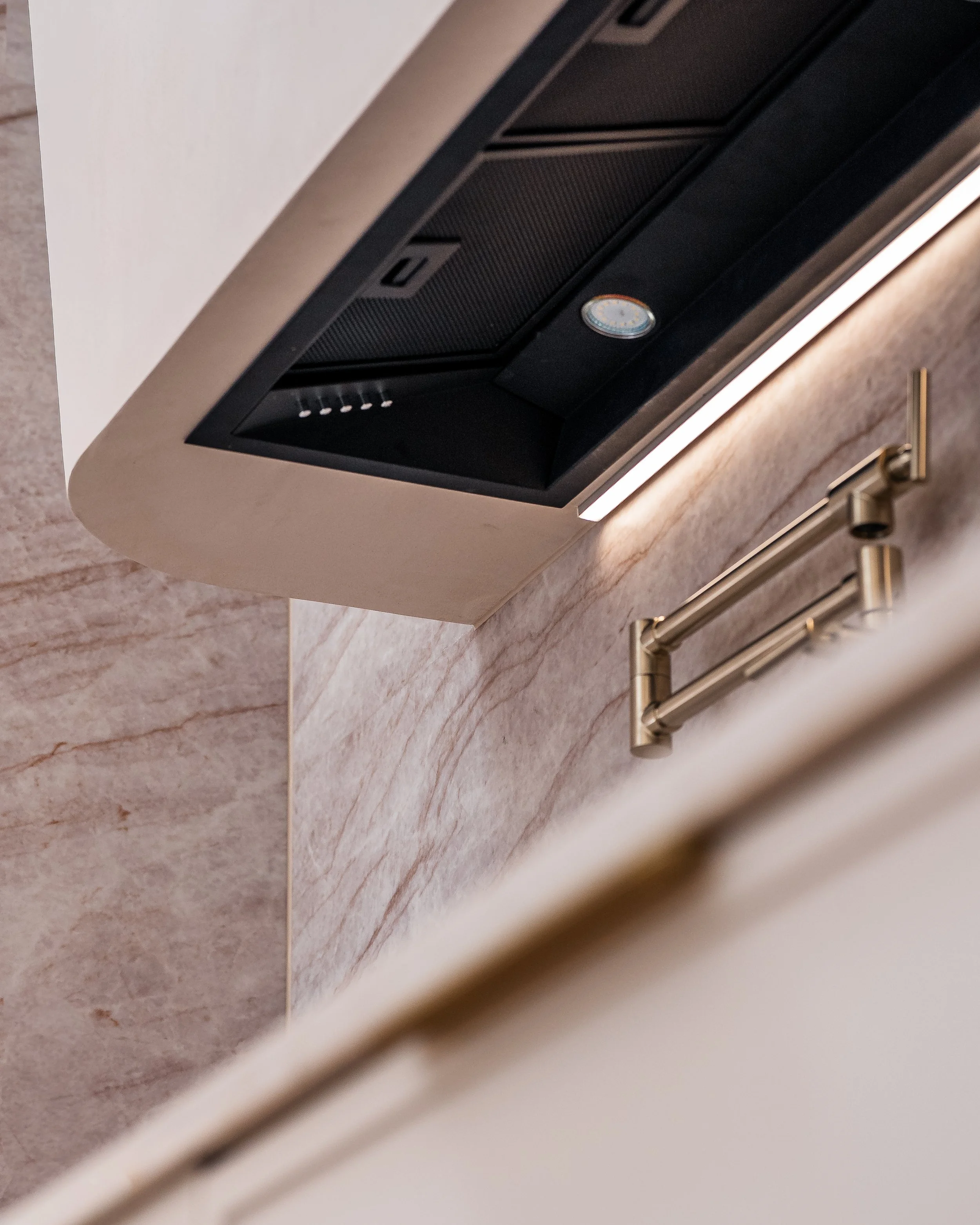 Close-up of an under-cabinet range hood with a wall-mounted clock visible in a kitchen setting.