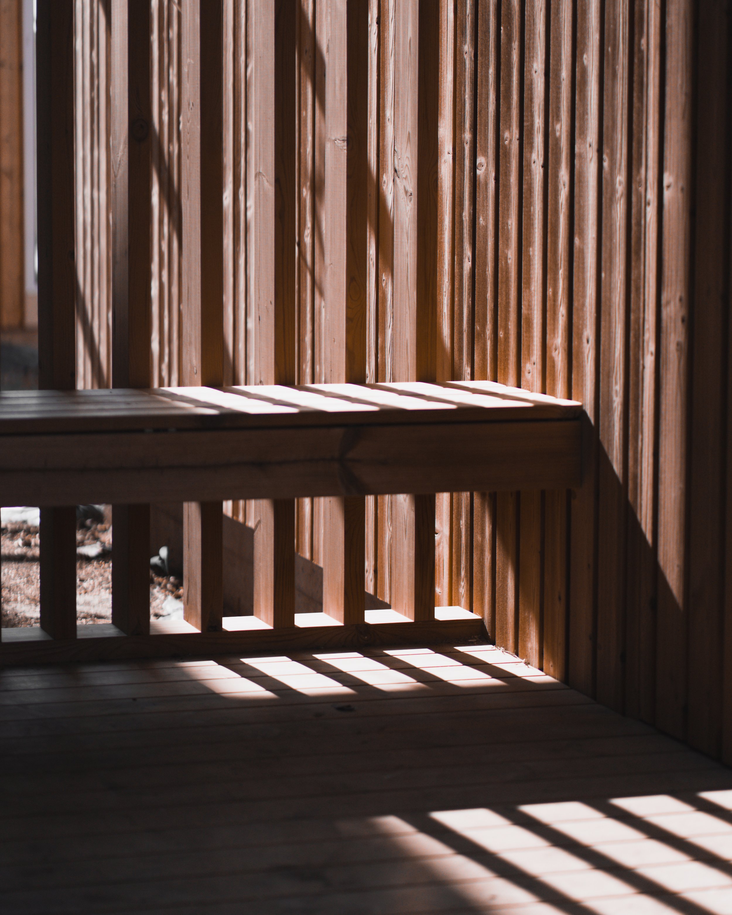 Wooden slat fence with shadows cast from sunlight.