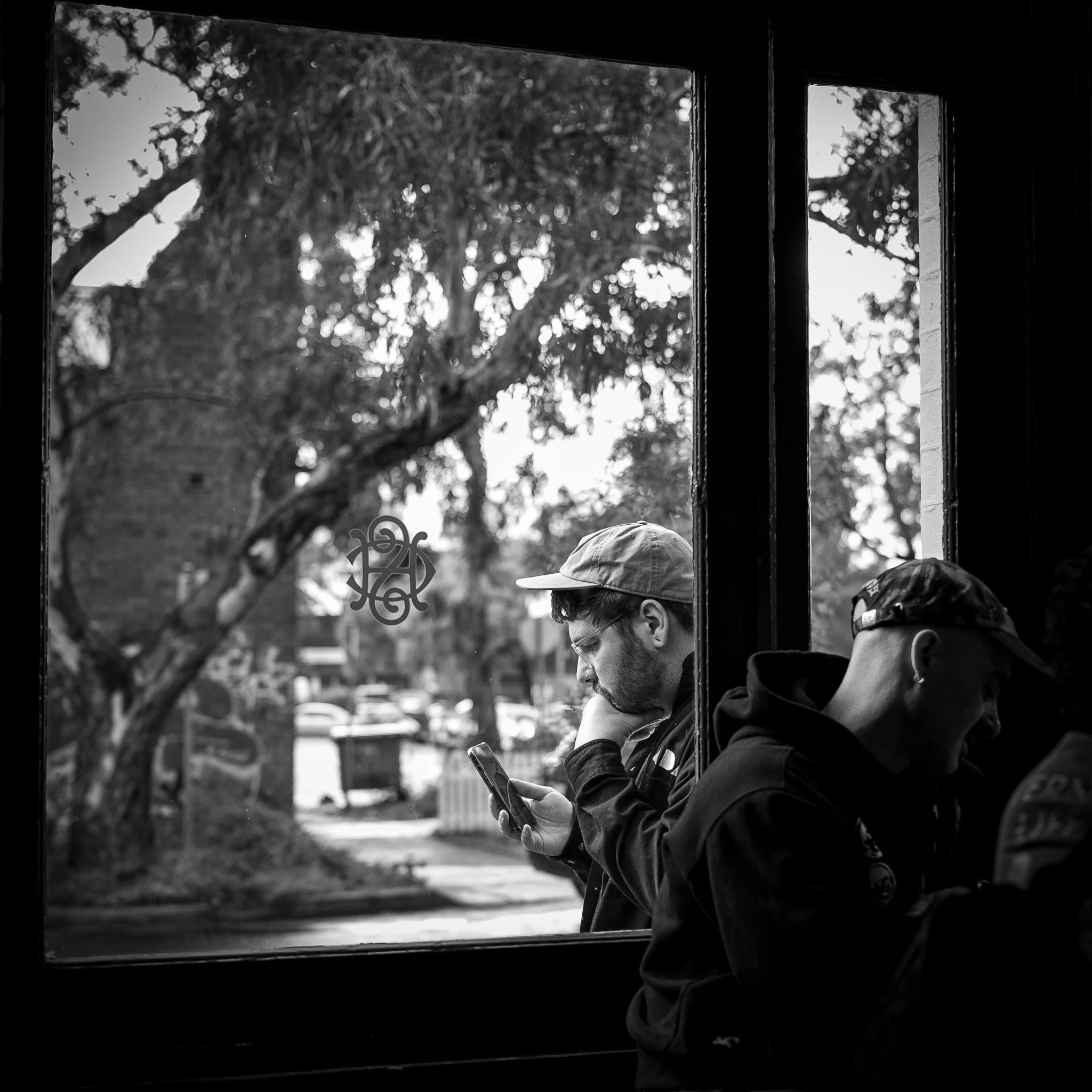 A man obsessed with his phone, outside of a vibrant Melbourne pub scene