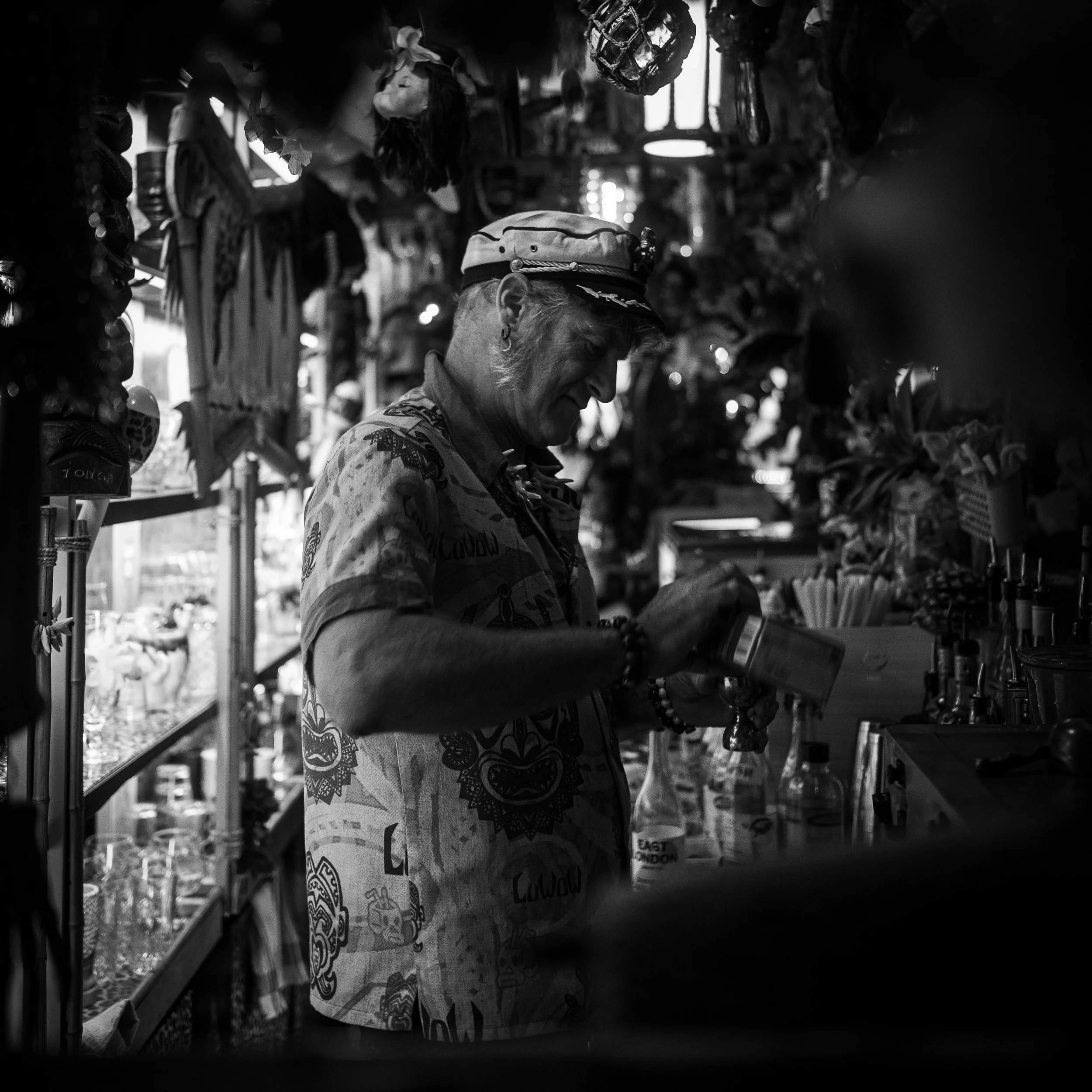 A person wearing a patterned shirt and hat shopping for jewelry at a store, with various accessories displayed around.