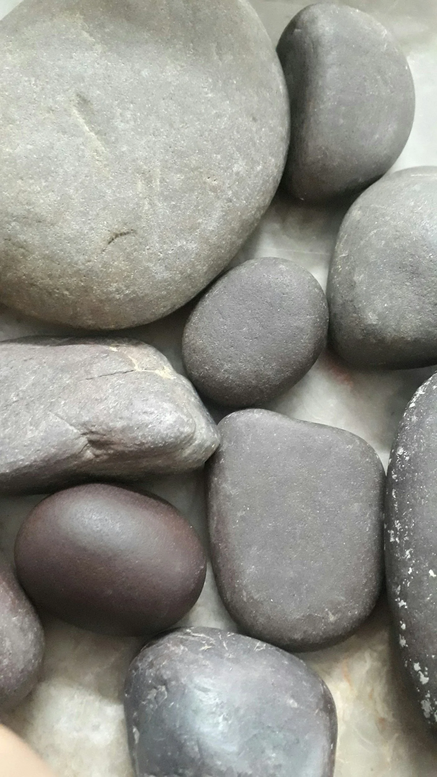 Close-up photograph of smooth, rounded gray and dark stones arranged together.