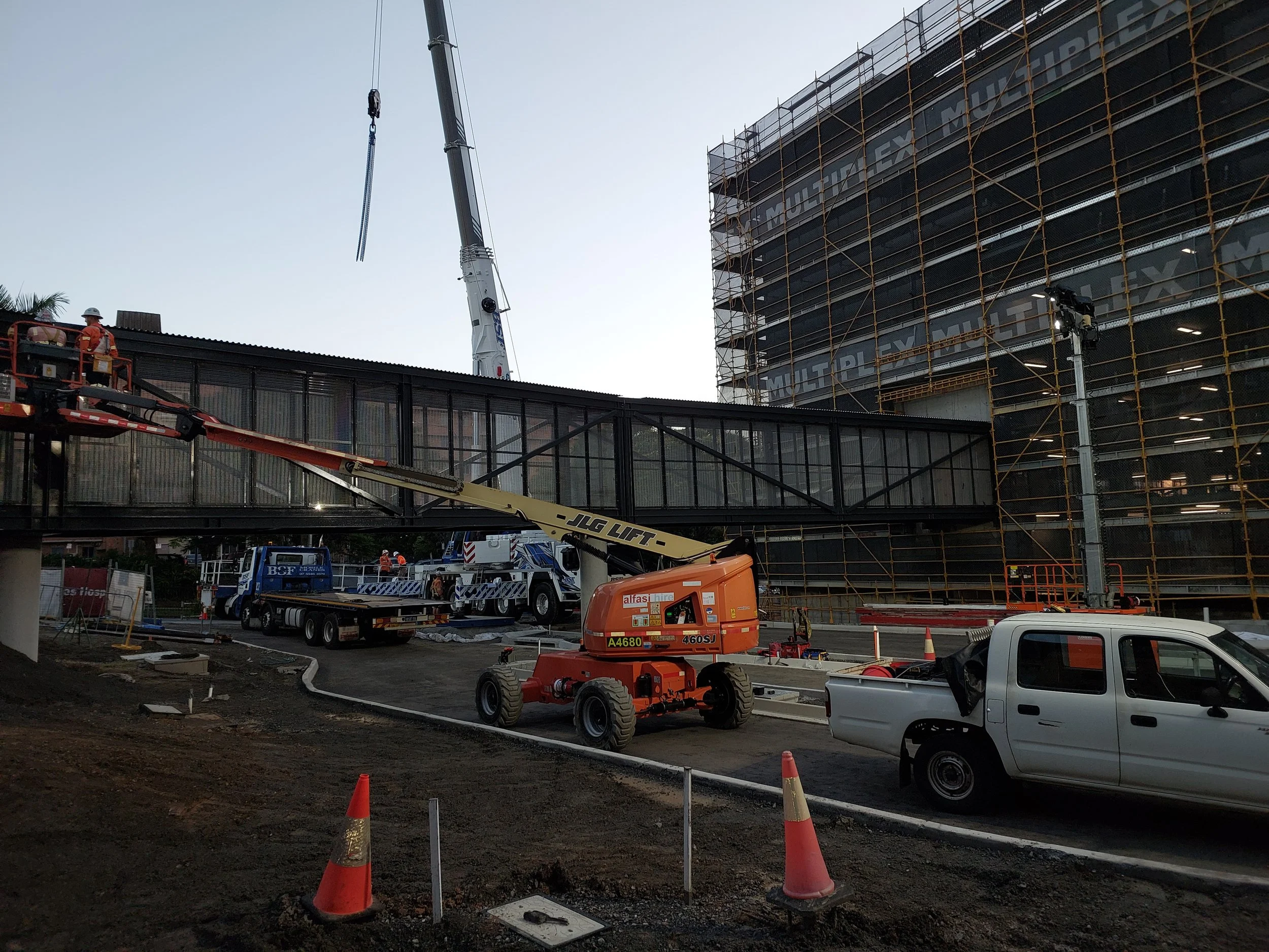 Construction site with workers, cranes, scaffolding, and vehicles working on a modern building structure.