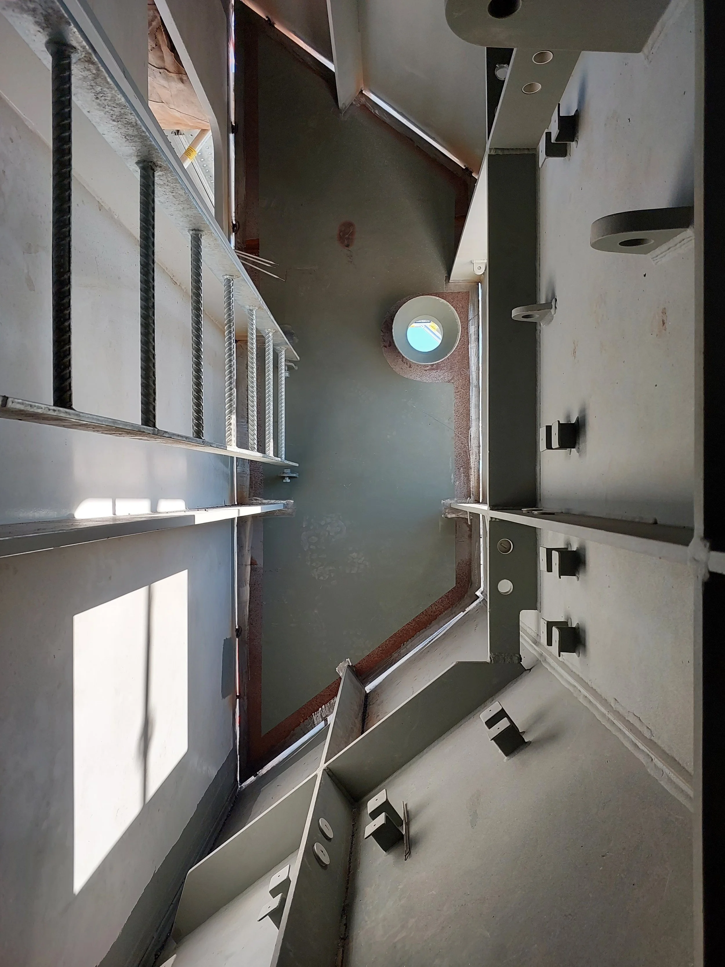 Empty kitchen with cabinets, a small window with sunlight, and construction materials like screws and brackets on the countertop.