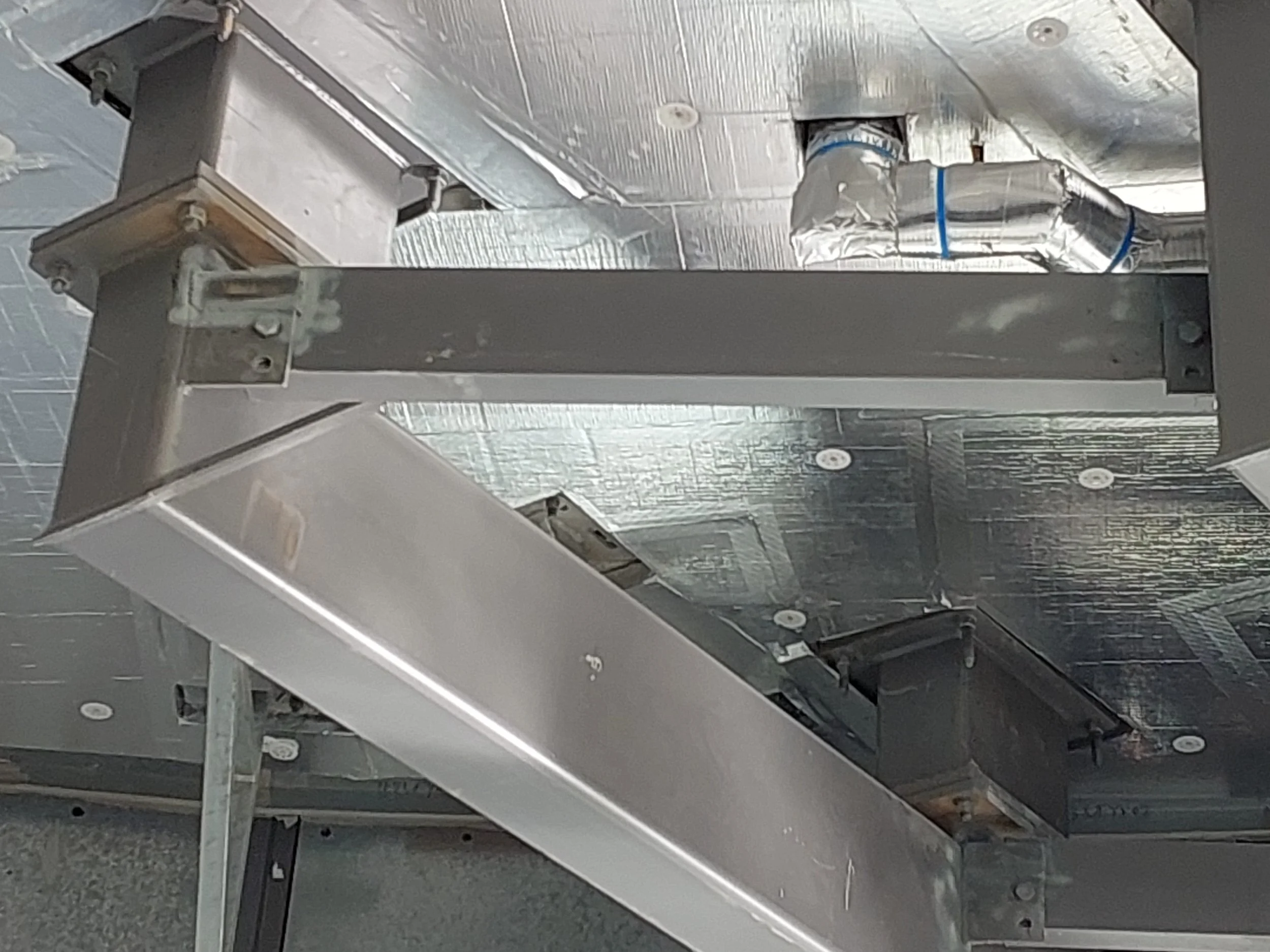 Close-up view of an unfinished metal construction or HVAC ductwork, with insulation and structural elements visible.