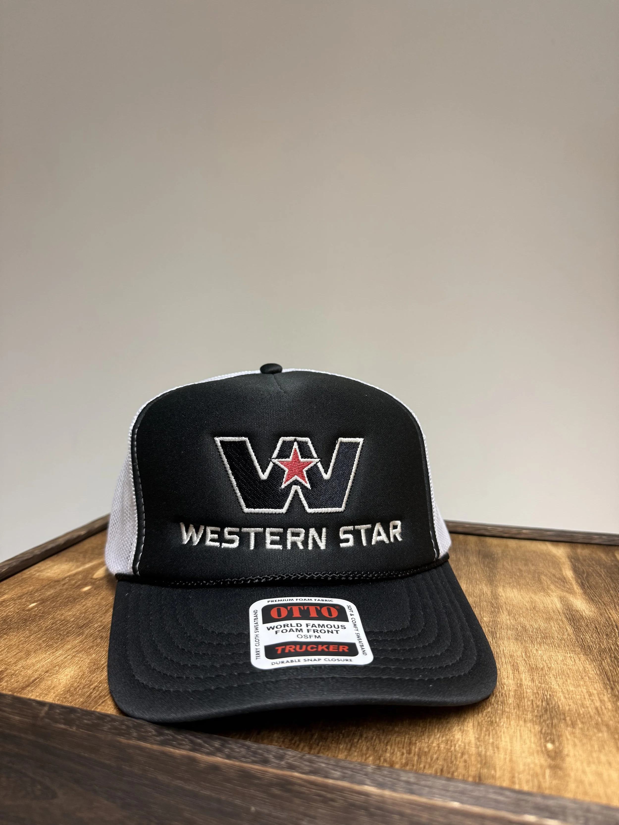 Black and white trucker hat with a red star, embroidered 'W' and 'Western Star' on the front, displayed on a wooden surface.