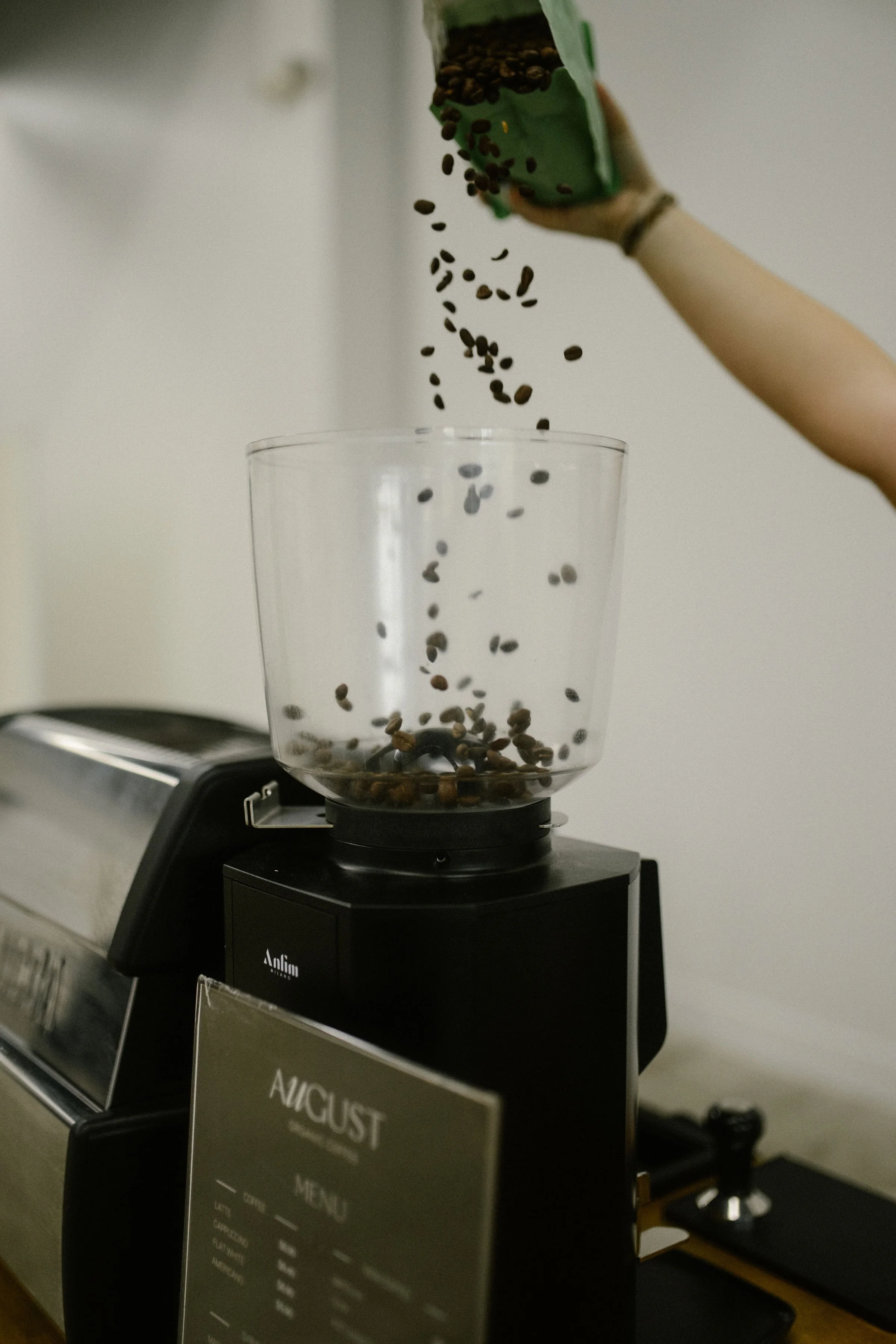 Coffee beans falling into a transparent container on a coffee grinder.