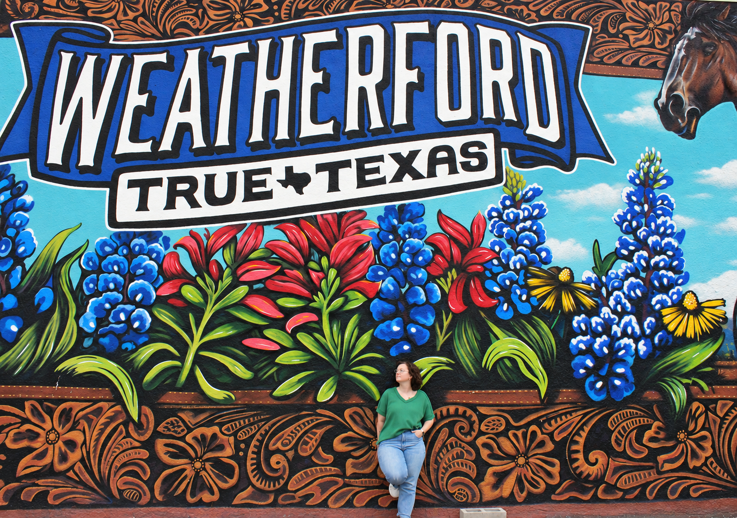 Kalli Stout standing in front of a colorful Weatherford, Texas mural