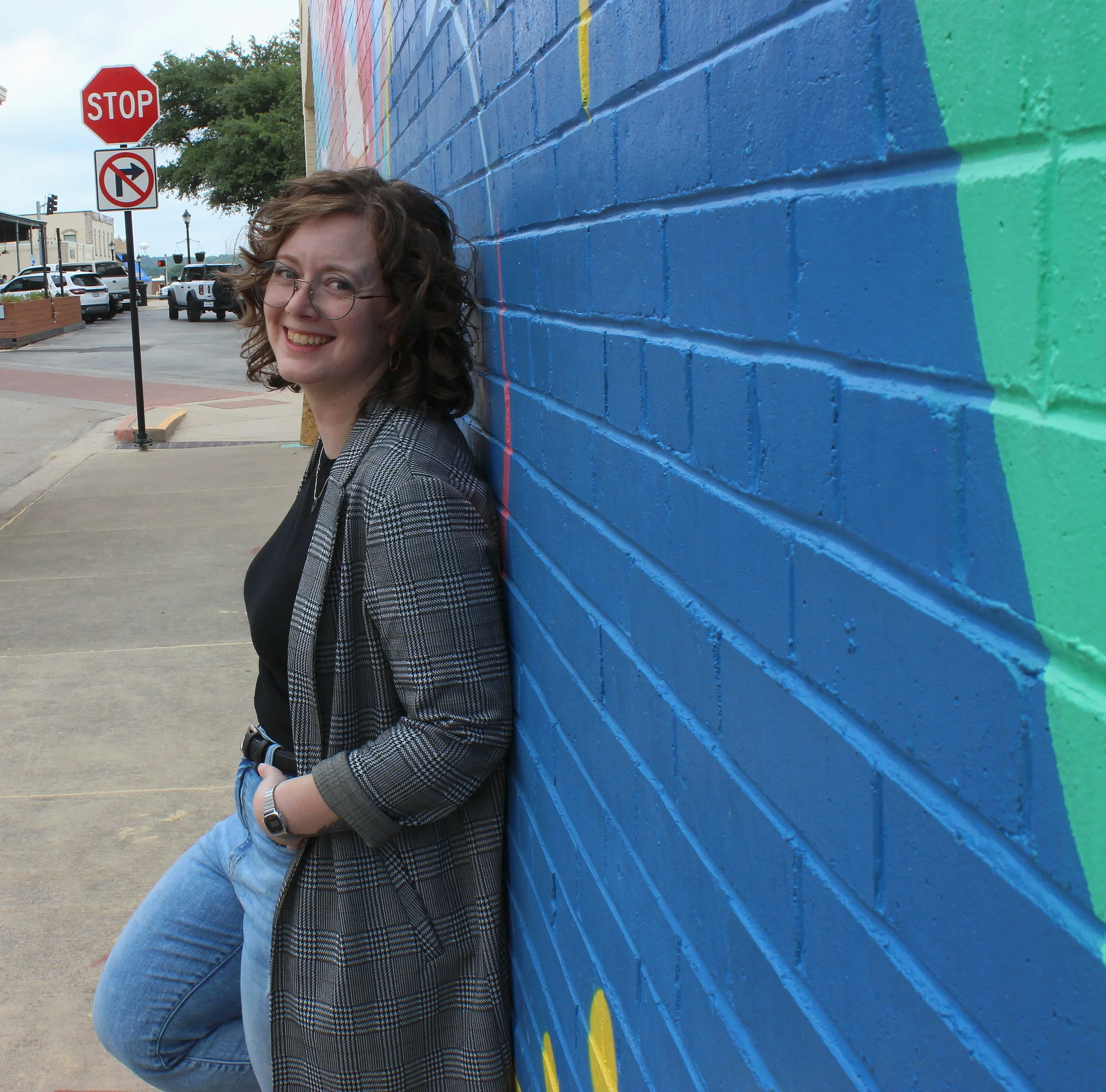 Kalli Stout smiling in front of a colorful mural in Weatherford, Texas.