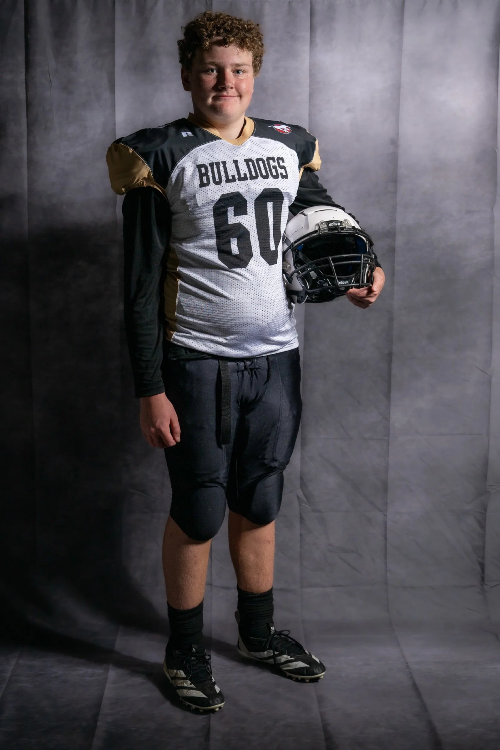 Football player in uniform holding a helmet during a portrait session