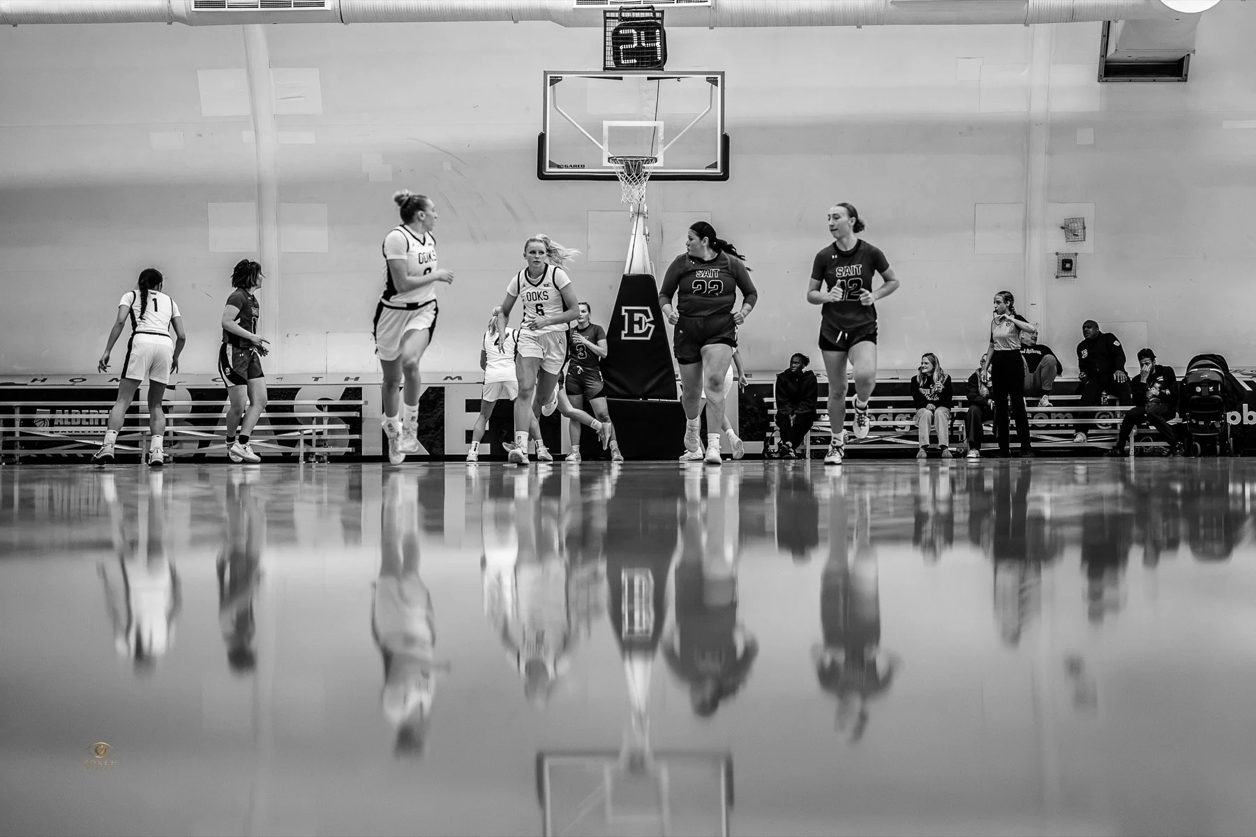 Basketball team gathered along the sideline with reflections on the court