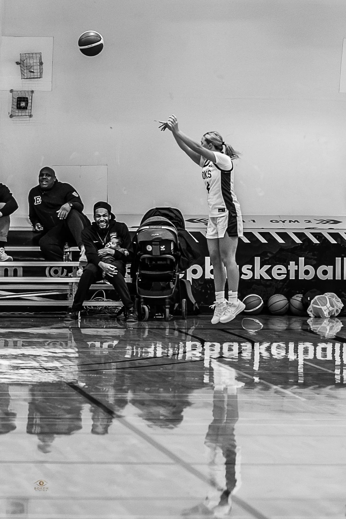 Basketball player rising for a shot as teammates and spectators watch