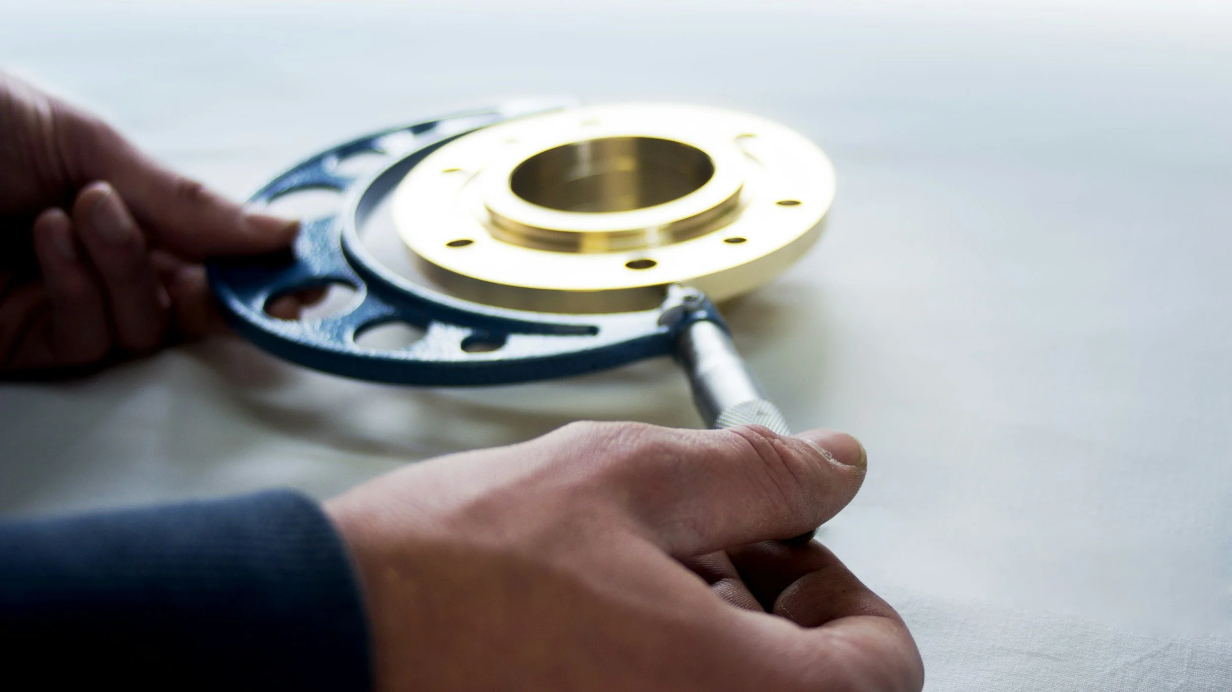 Person measuring a metal ring with a caliper.