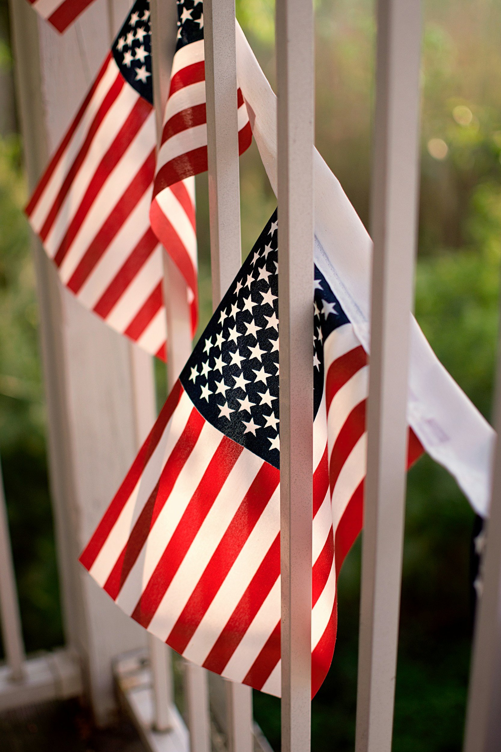 American flags hanging on a white railing.