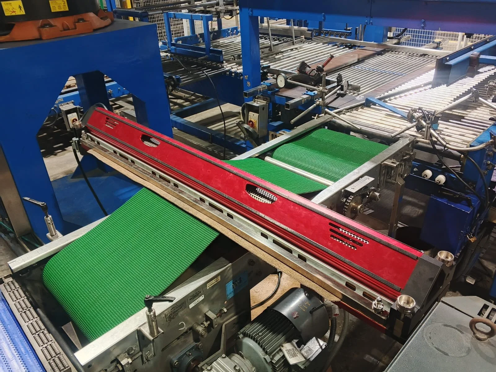 Maquinaria industrial de ensamblaje con cintas transportadoras verdes, componentes metálicos y partes de metal y plástico para ensamblar productos.
