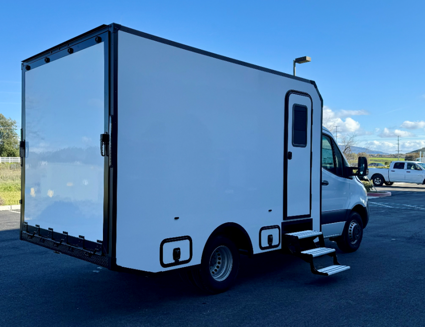 White delivery truck parked in a lot on a sunny day.