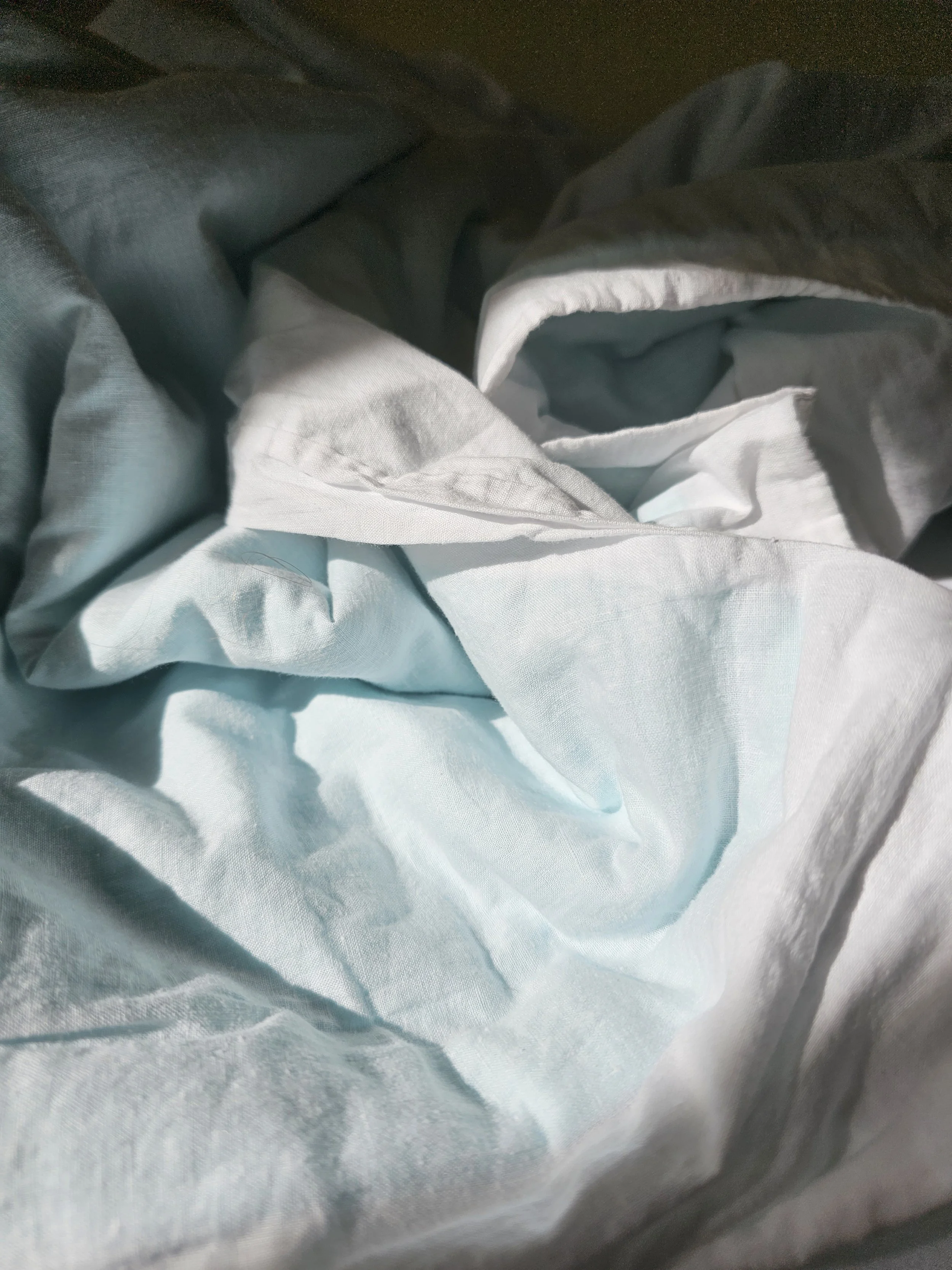 Close-up of crumpled light blue and white fabric, possibly clothing or bedsheet.