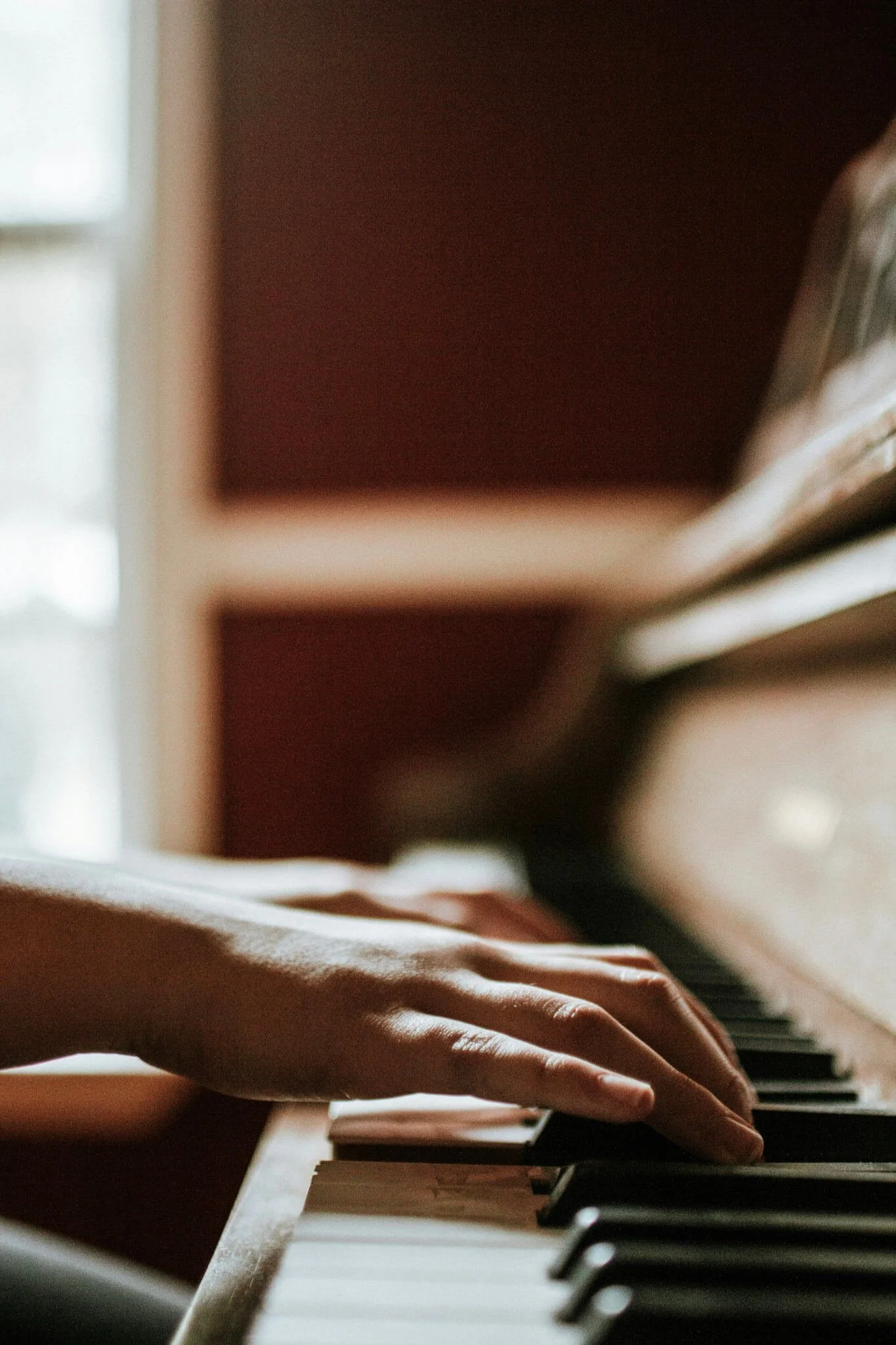Close-up of a hand playing piano keys in warm golden light, accompanying Vince Guaraldi's quote on staying true to yourself while embracing wide success, on Words That Stay.