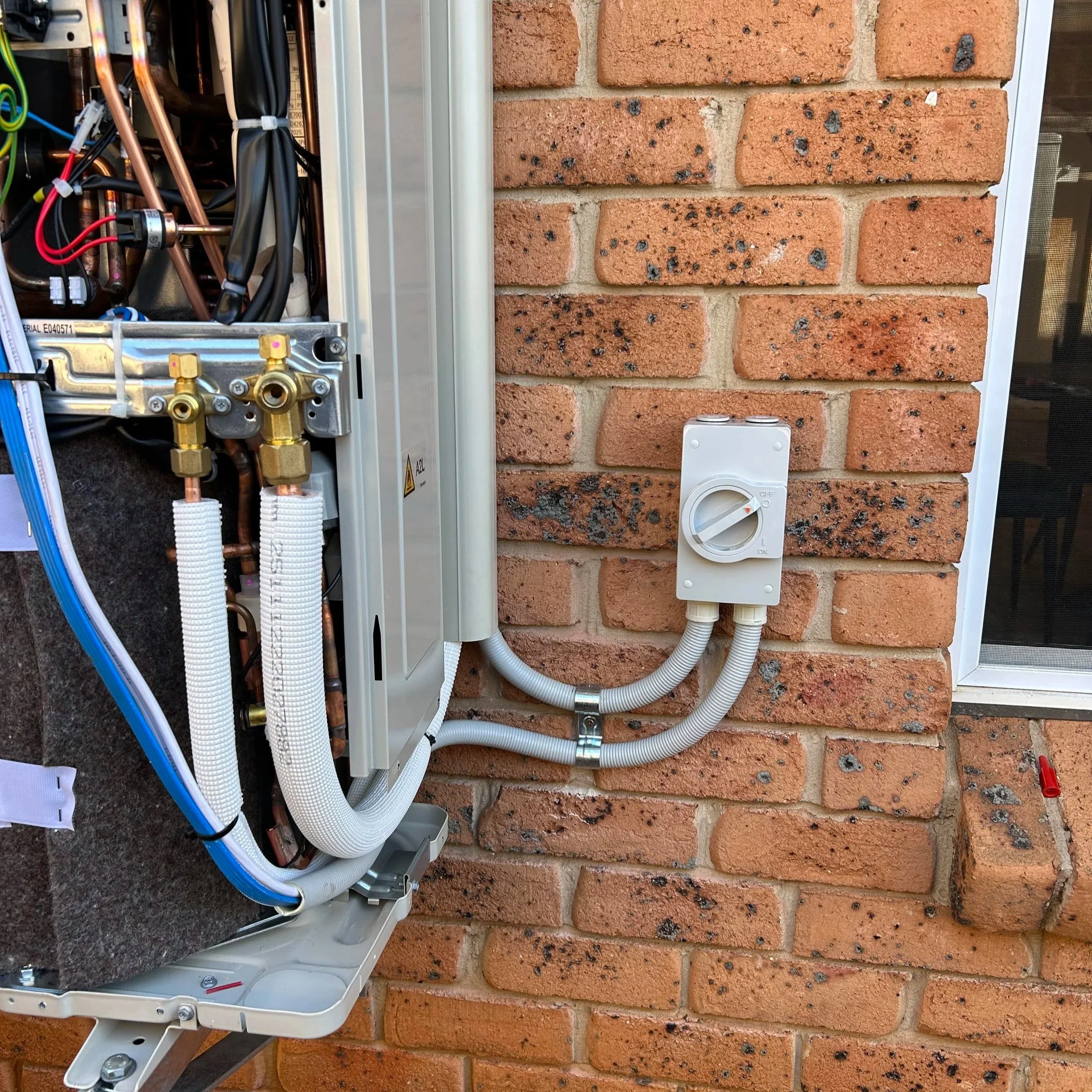 Close-up of electrical wiring and components installed on a brick wall.
