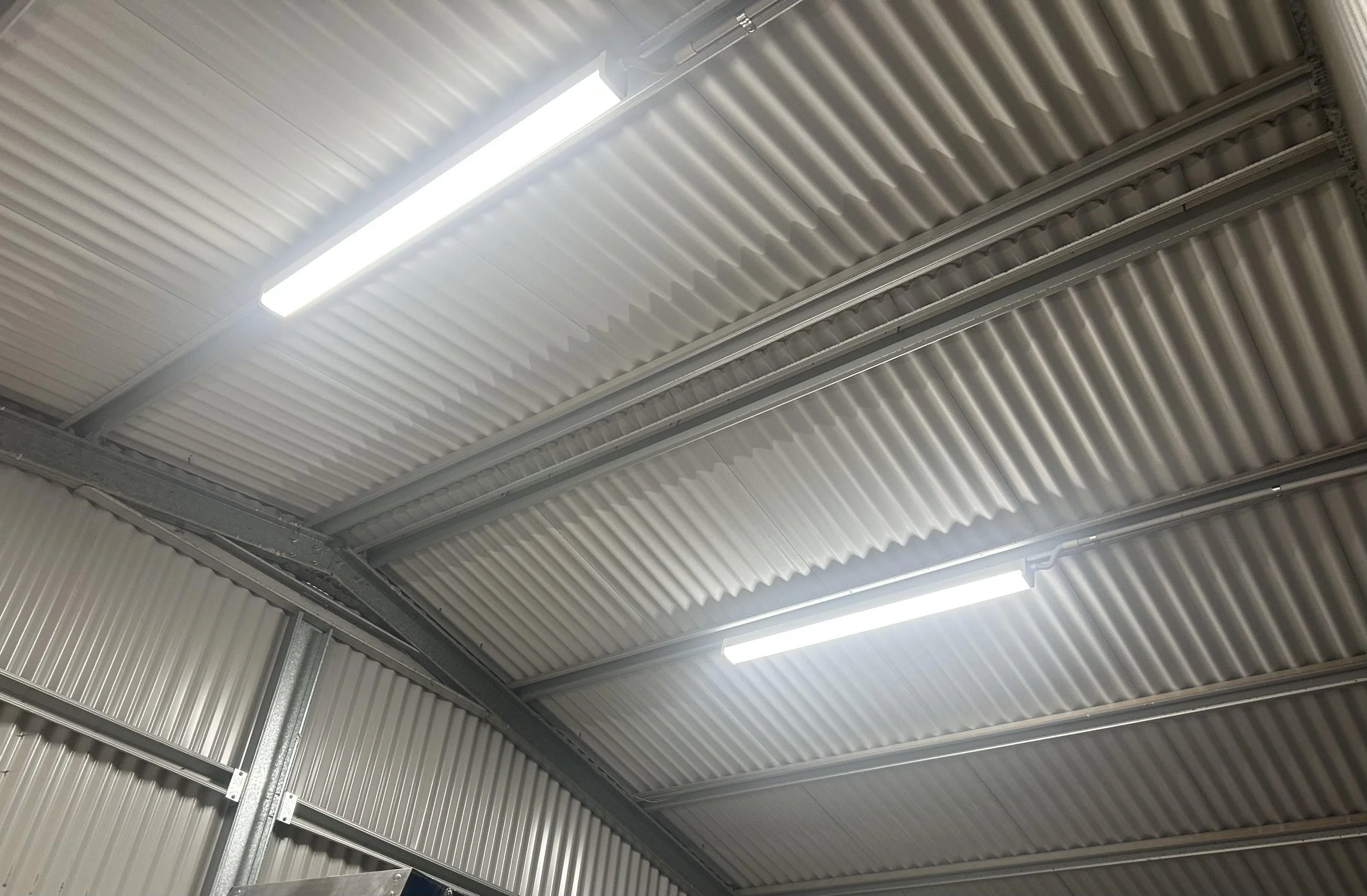 Metal ceiling panels with fluorescent lights in an industrial or warehouse setting.