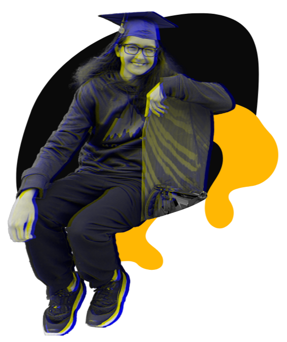 A young woman wearing a graduation cap, glasses, and a dark hoodie, smiling and sitting with one arm resting on her knee.