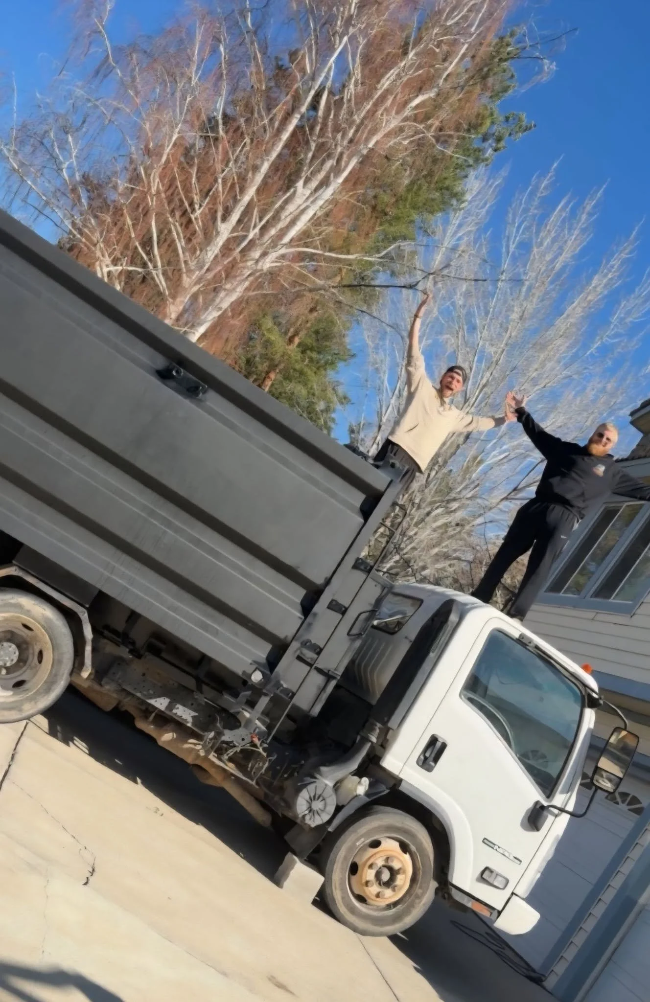 TNT Junk Removal team standing on company truck after startup journey
