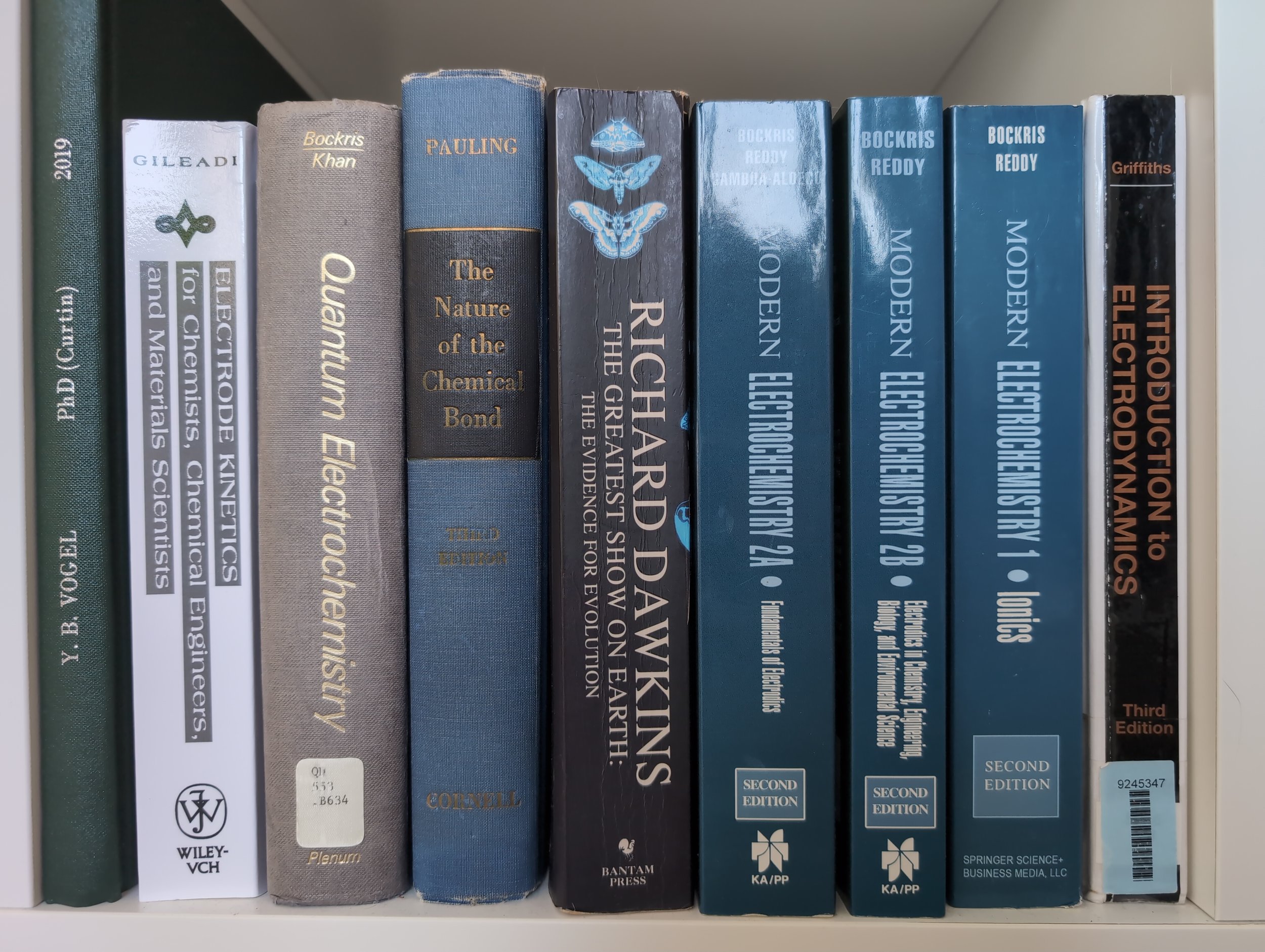 Close-up of a row of scientific textbooks on a bookshelf, including titles on chemistry, chemical bonds, and environmental science, with some books showing signs of wear.