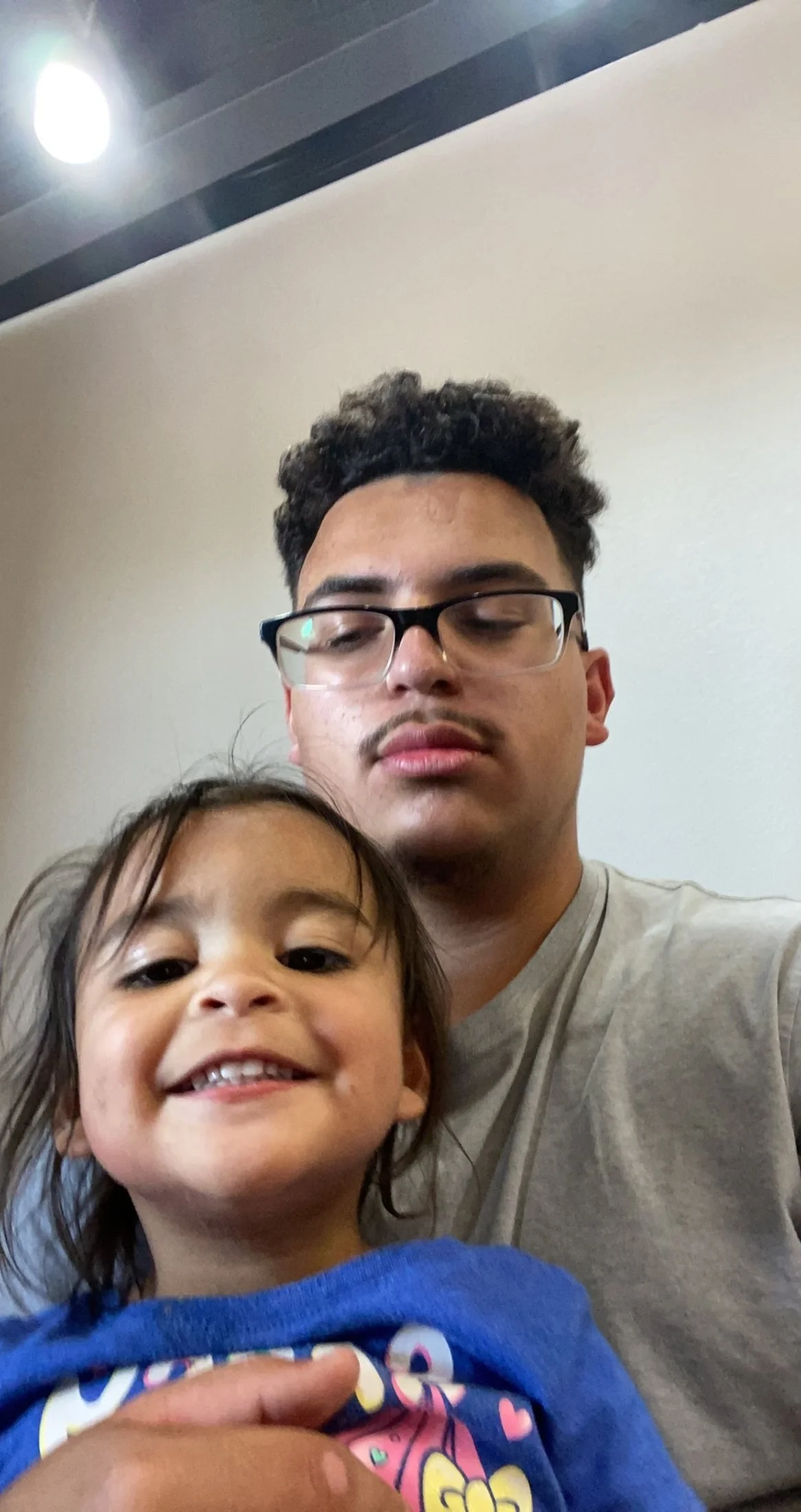 A young man with glasses and a small girl with wet hair taking a selfie together, both smiling.