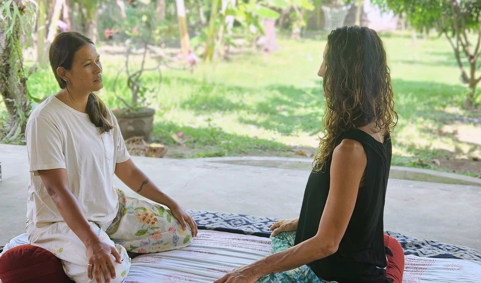 An outdoor one-on-one breathwork session with Mai and a student surrounded by a green garden.