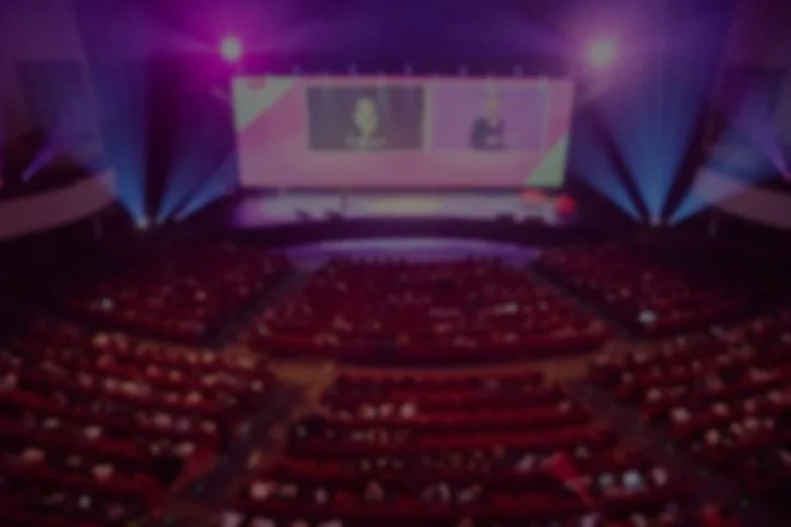 Grote auditorium met een groot scherm en kleurrijke lichtshows tijdens een evenement of conferentie.