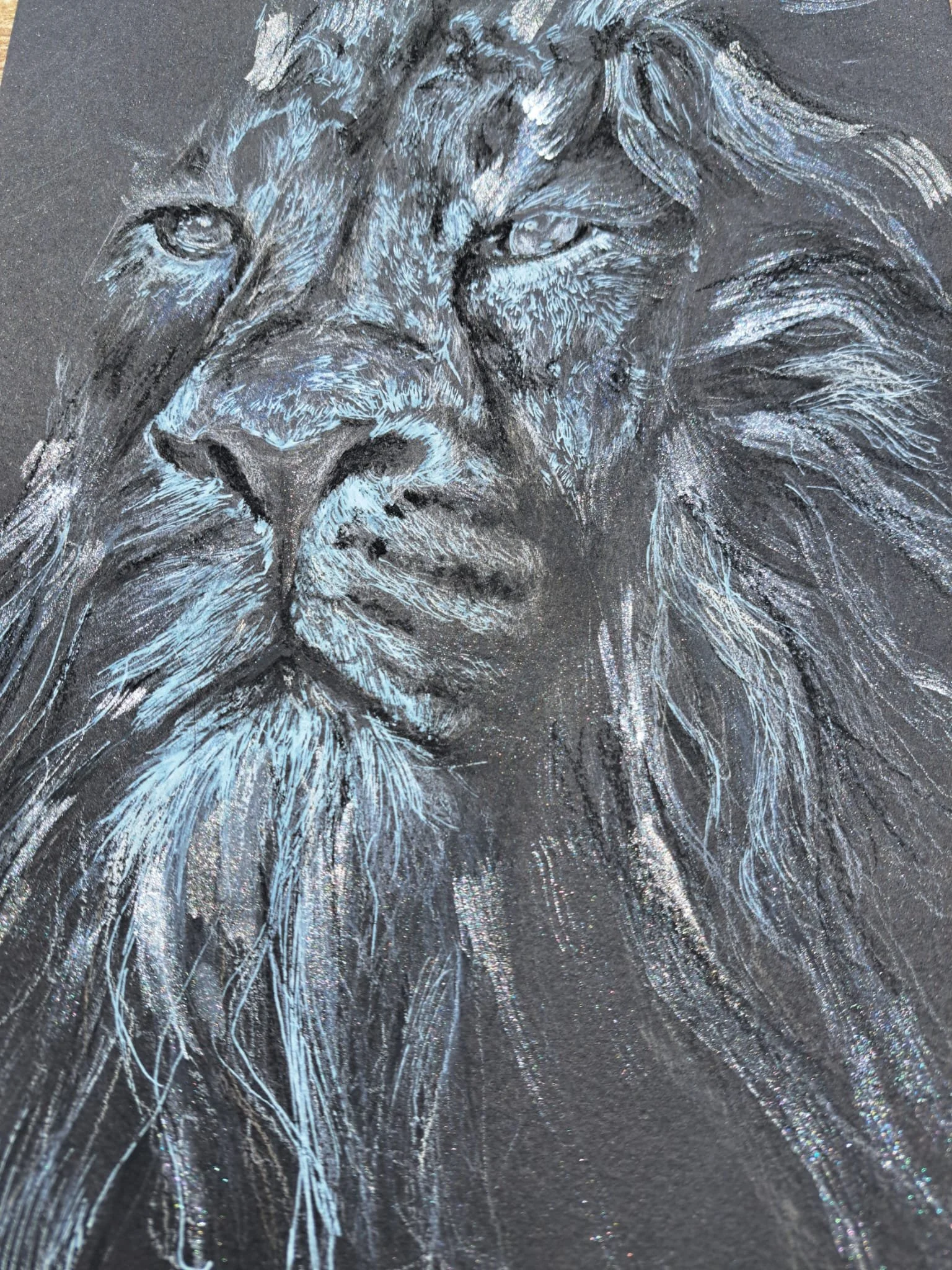 Retrato de un león dibujado con tiza en una pizarra negra, con detalles en blanco y gris.